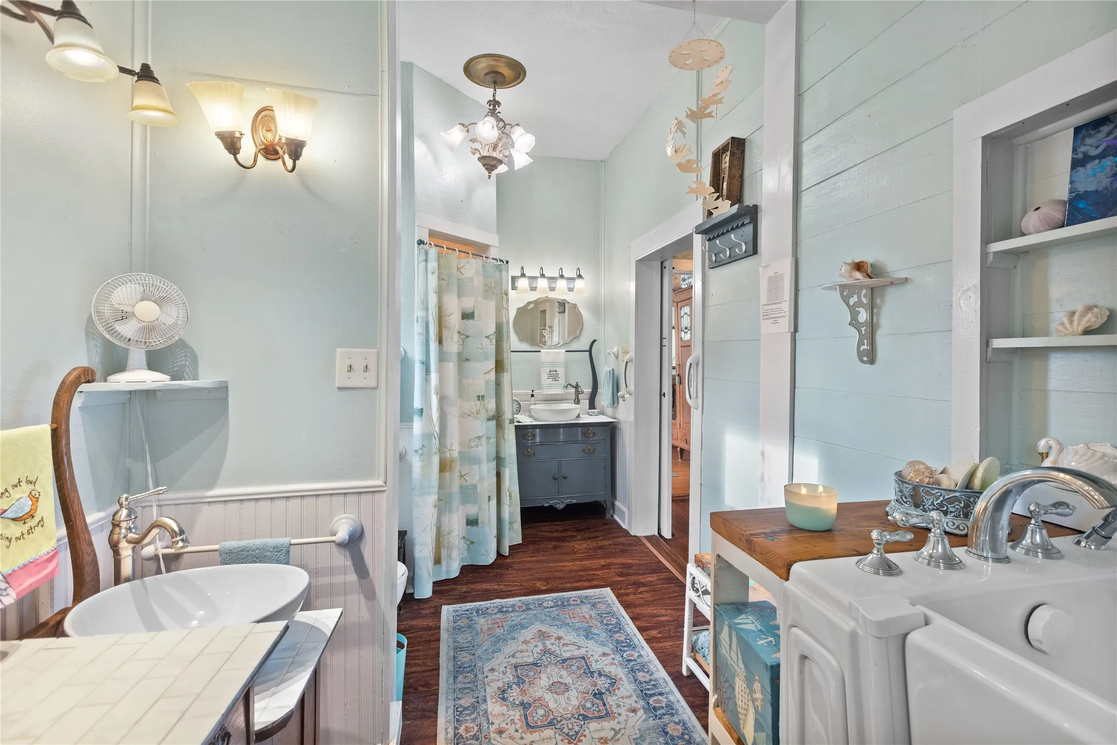 Downstairs primary Bathroom featuring wood-finish flooring, a vessel sink with wall-mounted faucet, and built-in shelving