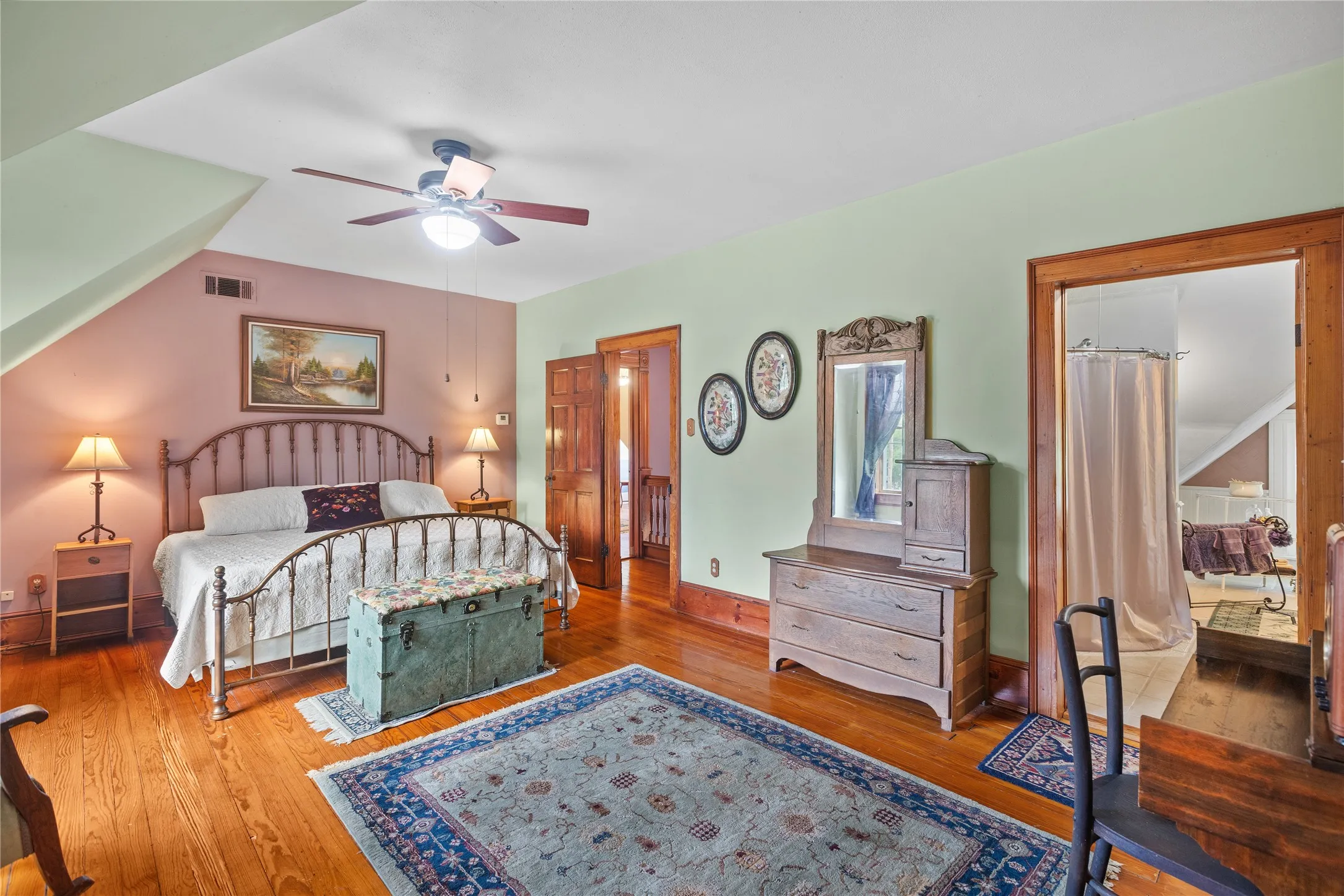 Upstairs primary bedroom w/Hardwood flooring throughout, ceiling fan with light fixture, and a spacious layout