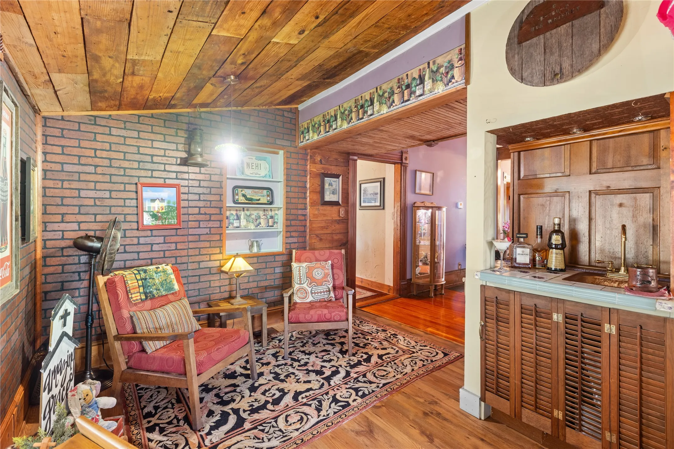 Exposed brick wall with built-in shelving, wood-finish flooring, and a paneled wood ceiling