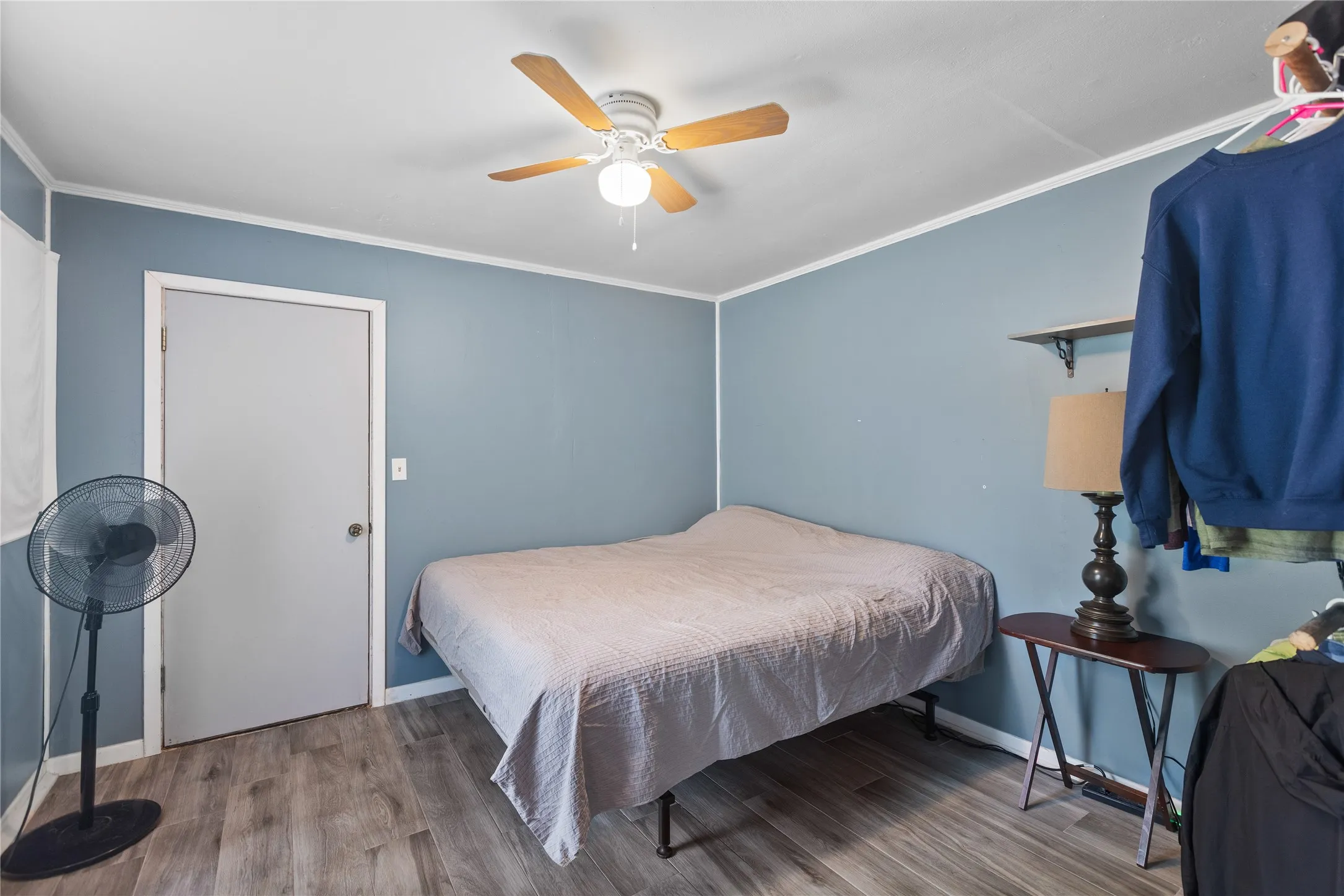 Dwelling 2 Bedroom or living room featuring wood-finish flooring, light blue walls, white trim, and a ceiling fan with light fixture