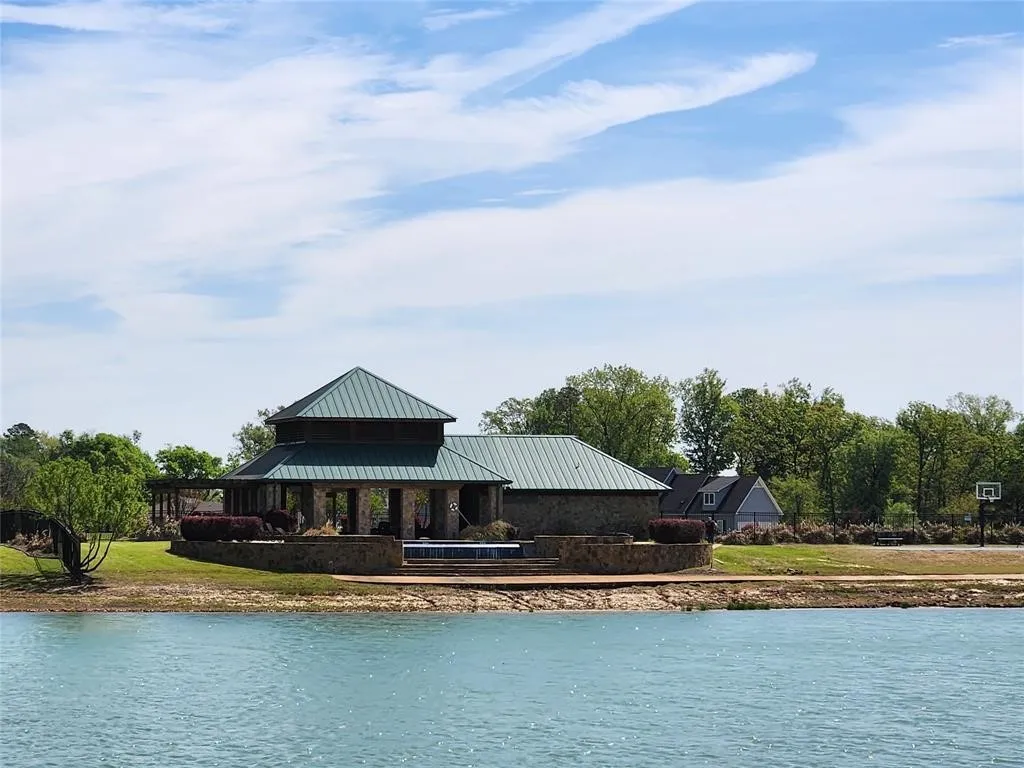 Stone structure with a green metal roof and an integrated pool, positioned waterside