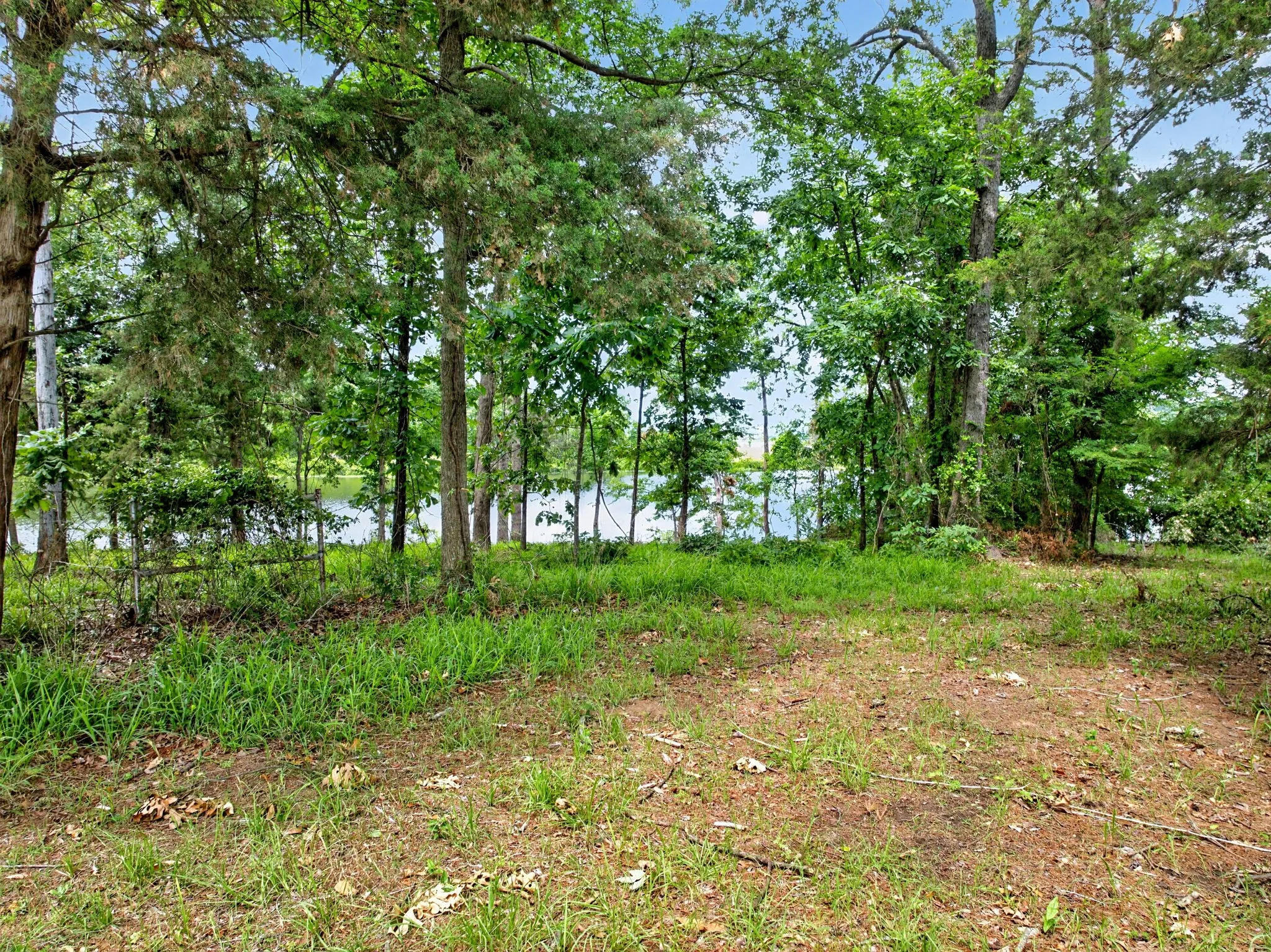 Wooded lot featuring a body of water visible through the trees