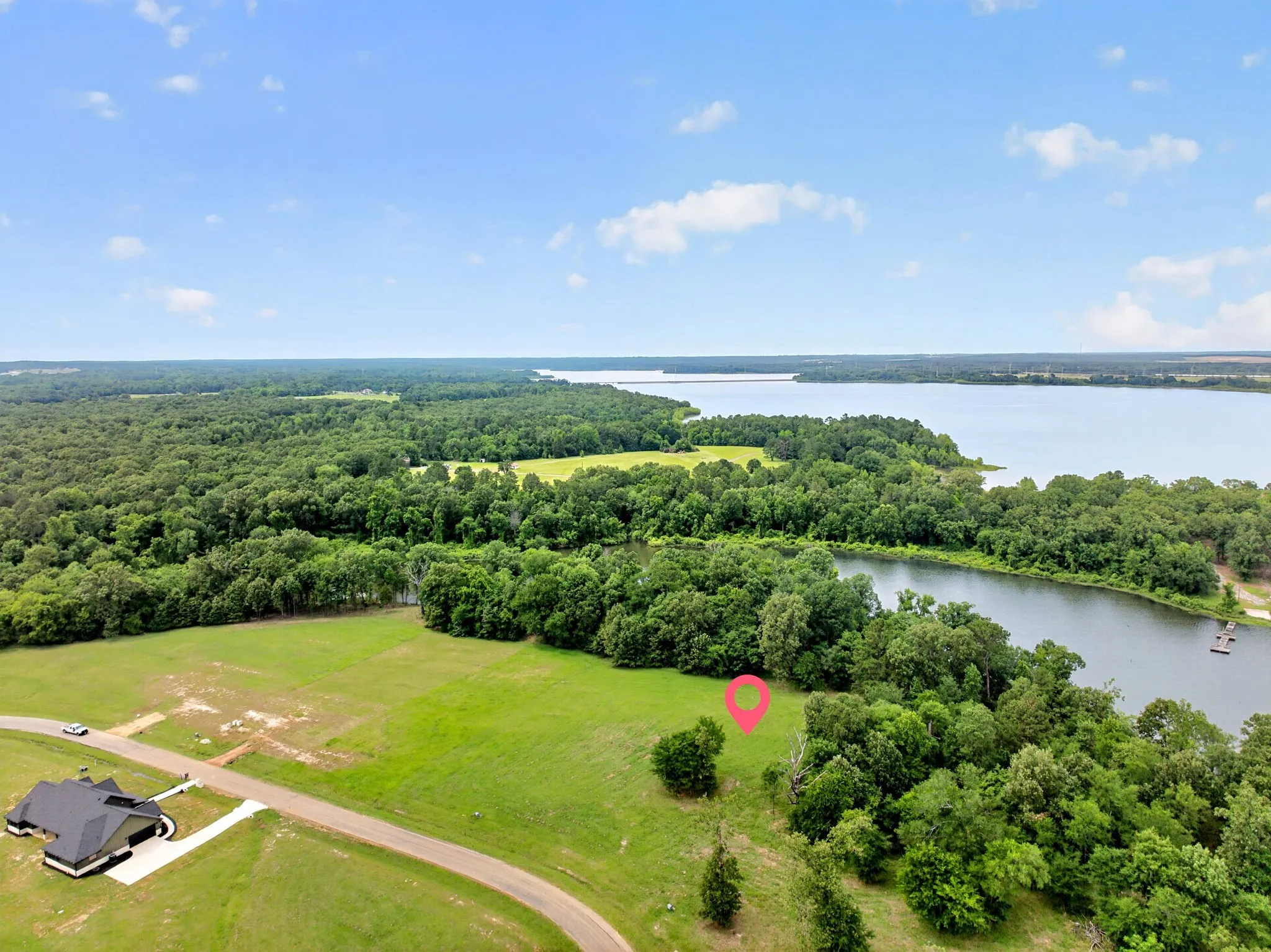 Expansive green space featuring mature trees and a lake boundary