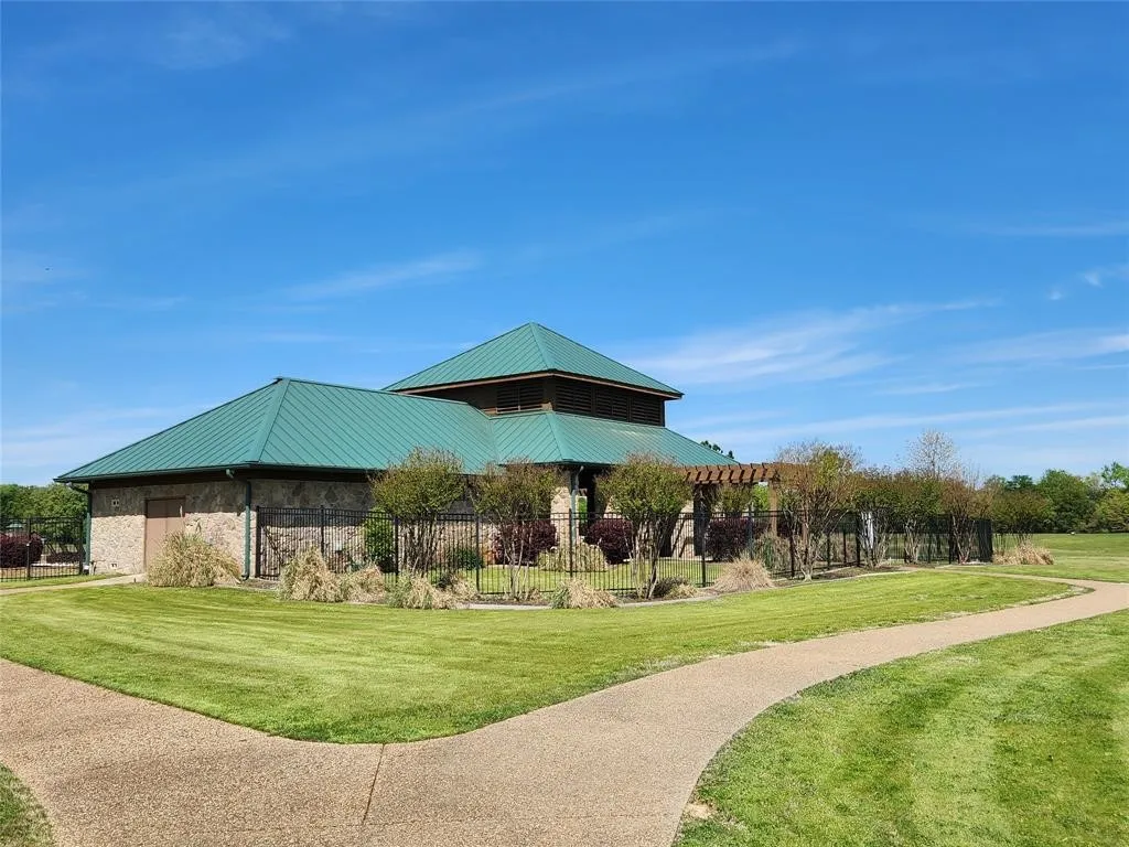 Building featuring a green metal roof, stone facade, and a prominent pergola structure