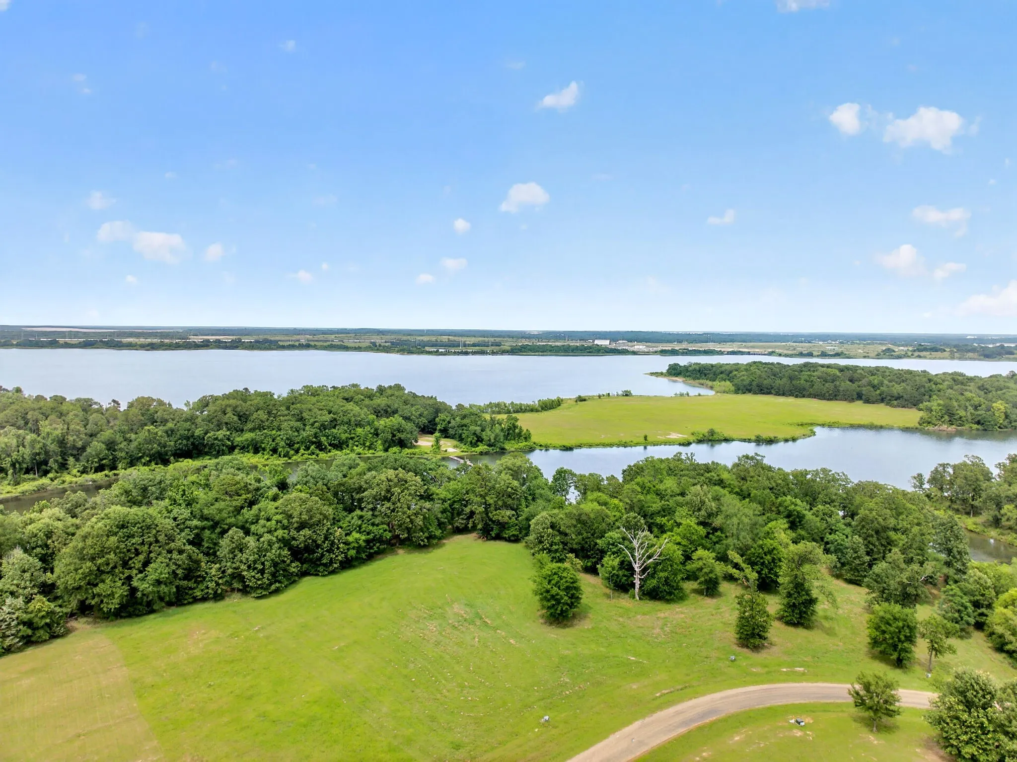 Expansive waterfront acreage featuring a large lake, verdant islands, mature trees, and open green spaces