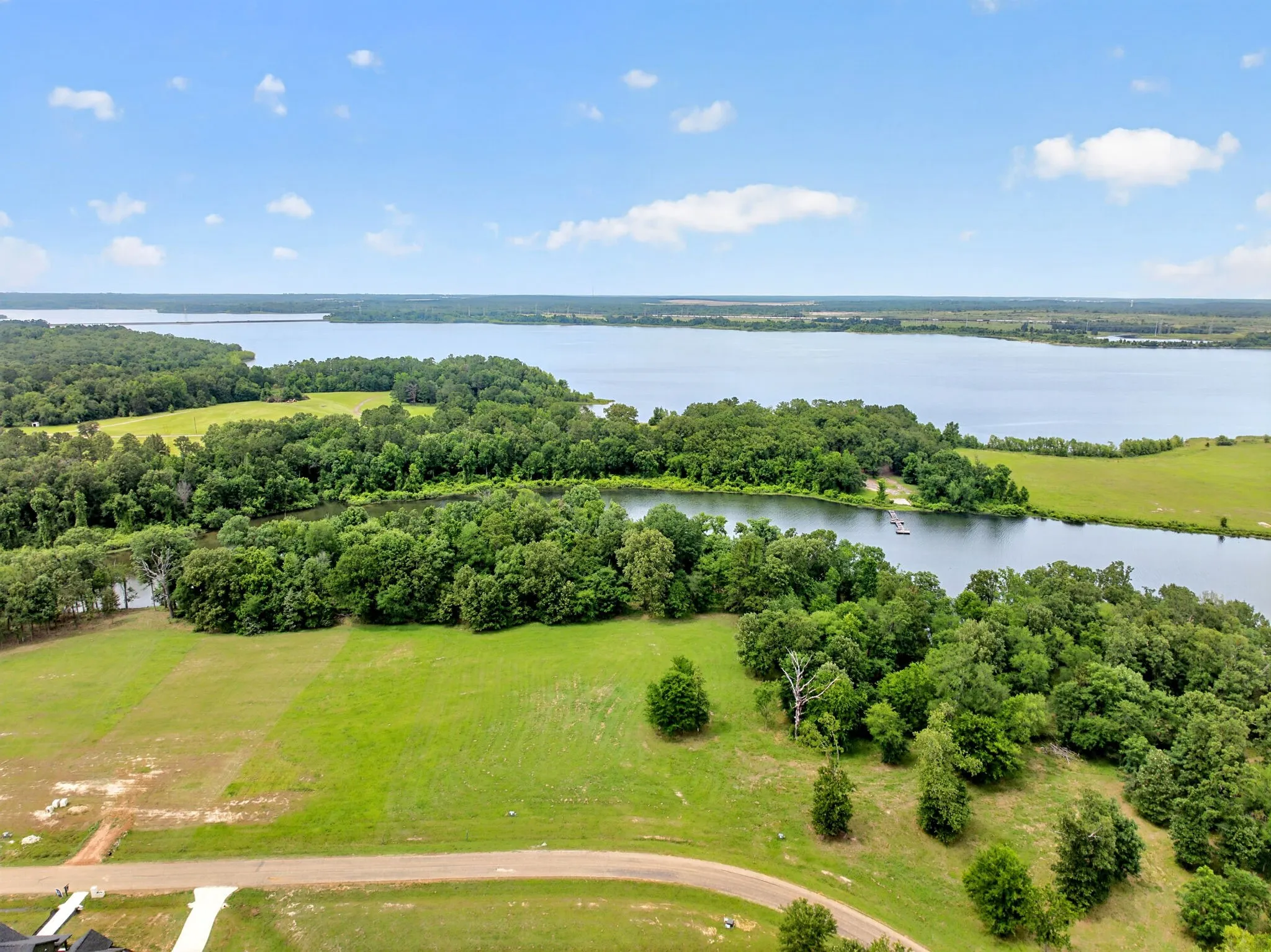 Expansive waterfront property featuring mature tree lines, open green spaces, and direct water access