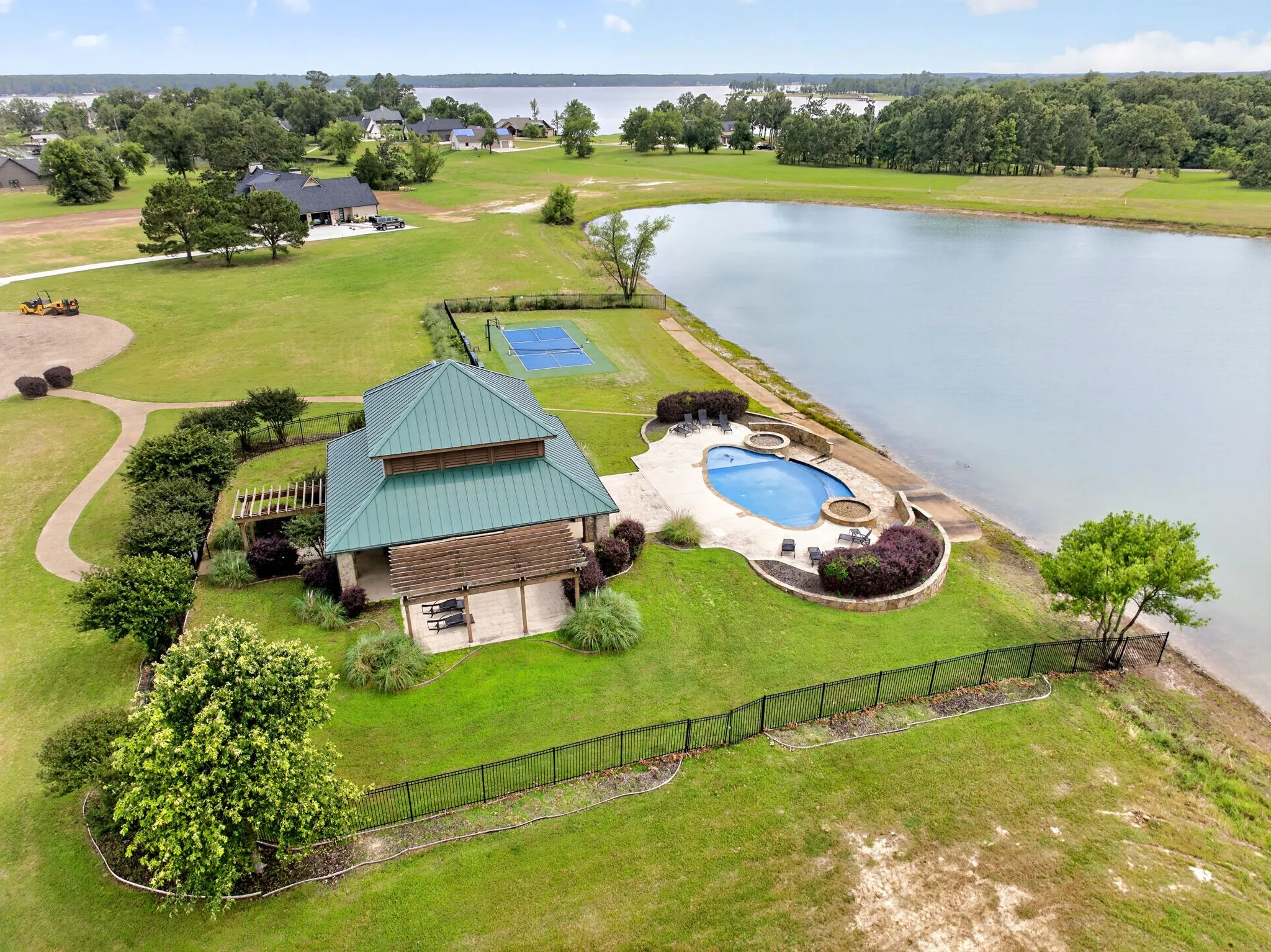 Lakeside amenity center featuring a swimming pool, spa, covered patio, and sports court