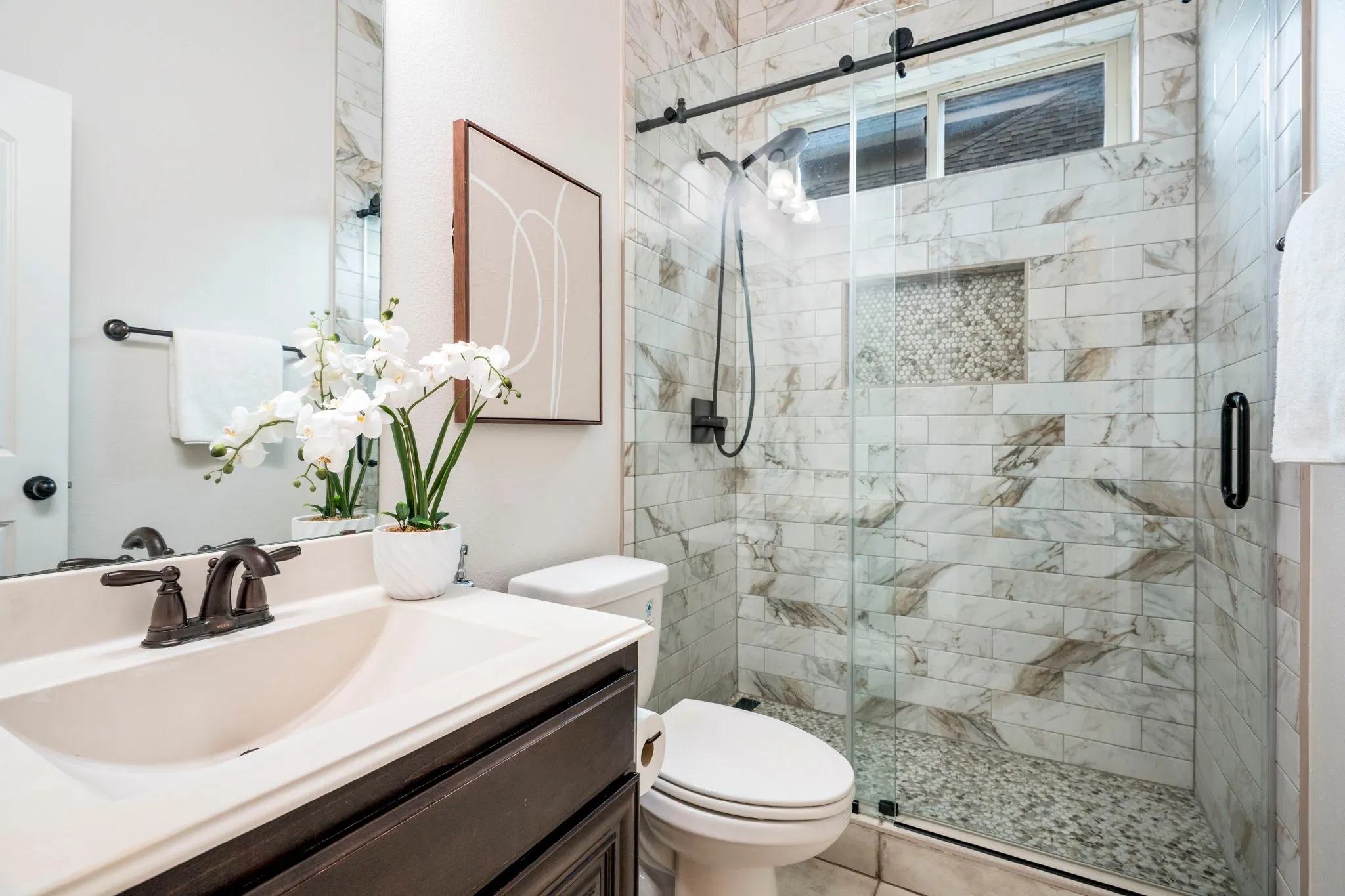 Perfectly suited for multi-generational living, the main-level bedroom and full bath provide comfort and convenience, highlighted by an updated bathroom featuring elegant tile finishes and modern glass sliding doors.