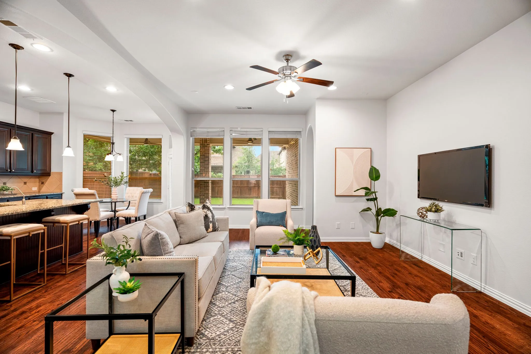 The open floorplan seamlessly connects the living room to the kitchen, creating an ideal space for modern living, while a stunning wall of windows frames beautiful backyard views and fills the home with natural light.
