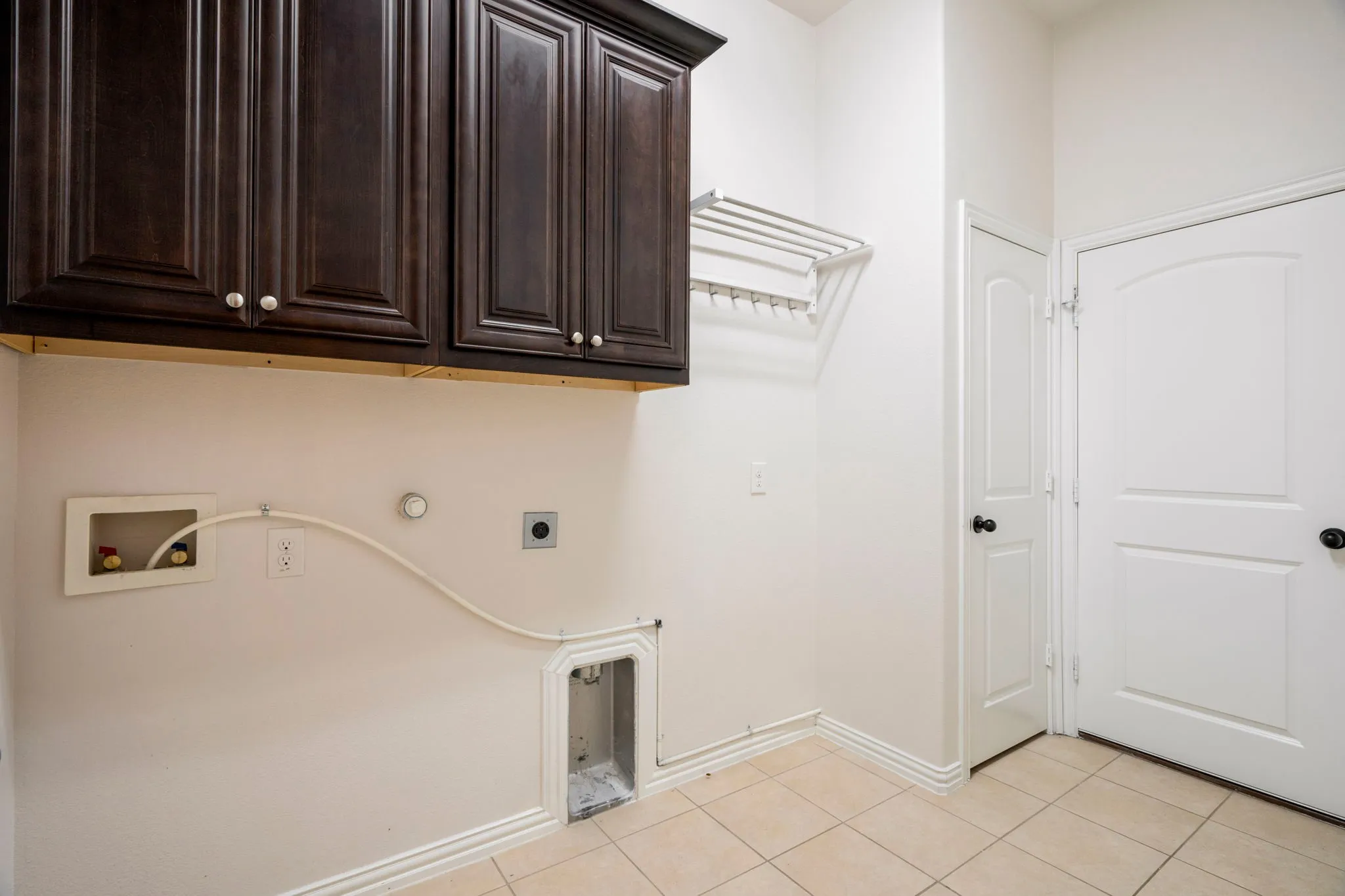 This well-appointed laundry room features built-in cabinets for organization, along with space for a second fridge and room to hang laundry for air drying, making daily chores more efficient.