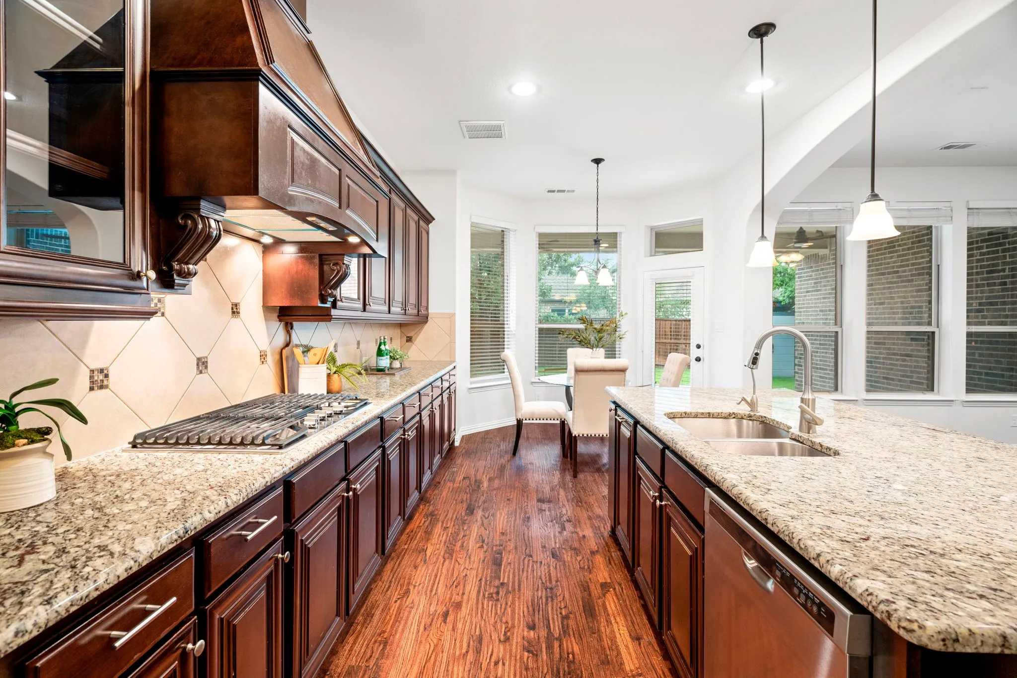 The kitchen showcases rich wood cabinetry, a gas cooktop, and stainless steel appliances, creating a warm and functional space designed for everyday cooking and effortless entertaining.