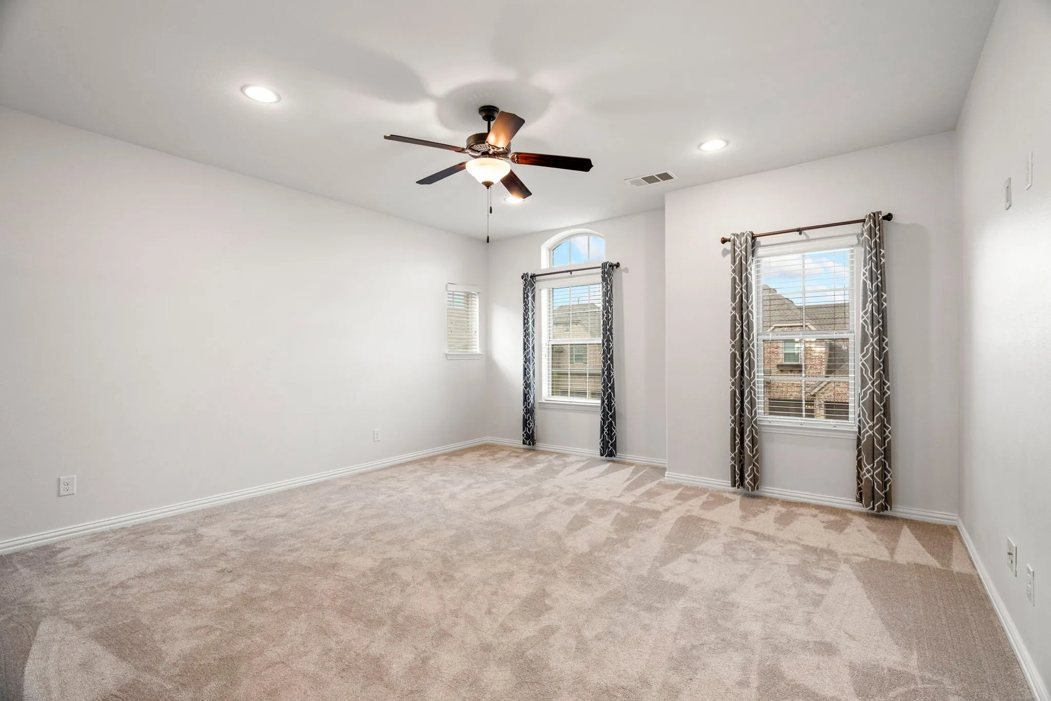 This light-filled game room offers a spacious layout and sunny atmosphere, with windows that frame peaceful views of the front yard, making it an ideal hangout for kids or a flexible second living area.
