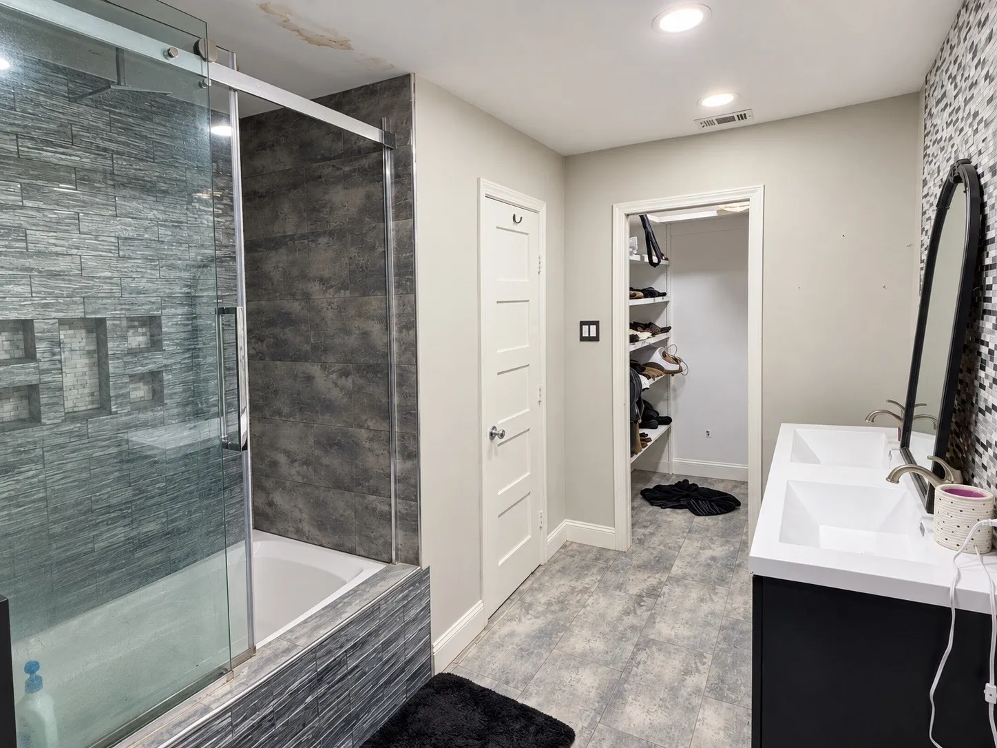 Walk-in shower with glass enclosure and dark gray tile surround