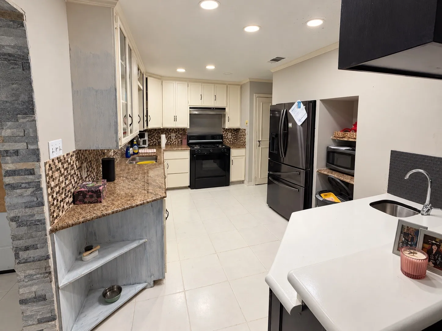 Cream-colored cabinetry with glass-front accents, mosaic tile backsplash, polished granite countertops, and recessed lighting