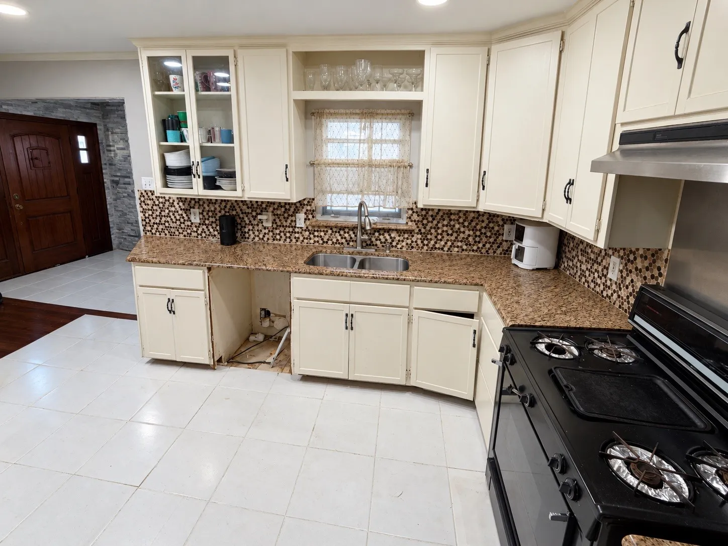 Kitchen featuring white cabinetry, a dual basin sink, a mosaic tile backsplash, and granite-style countertops