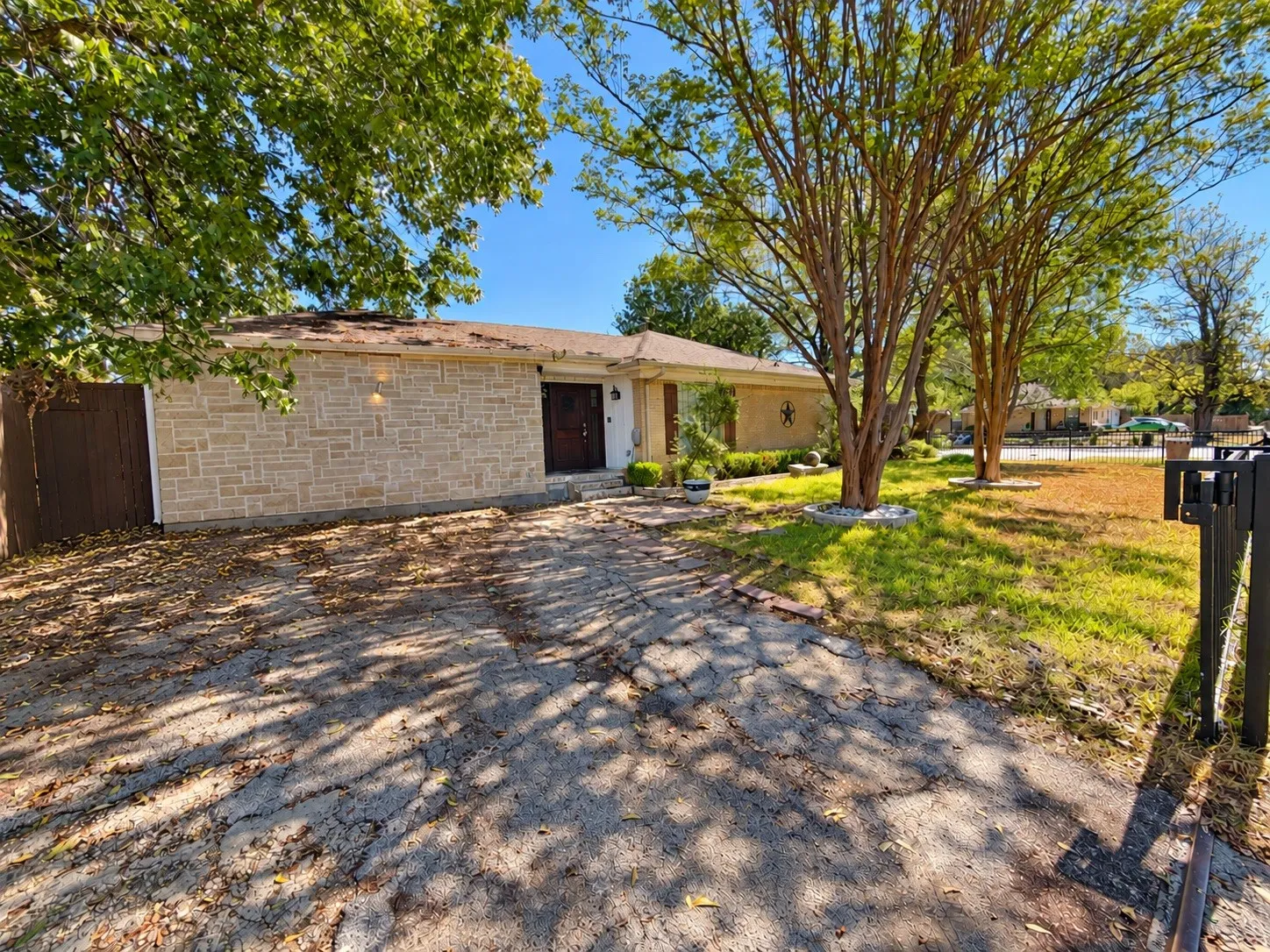 Stone veneer exterior with a wood privacy fence and mature landscaping