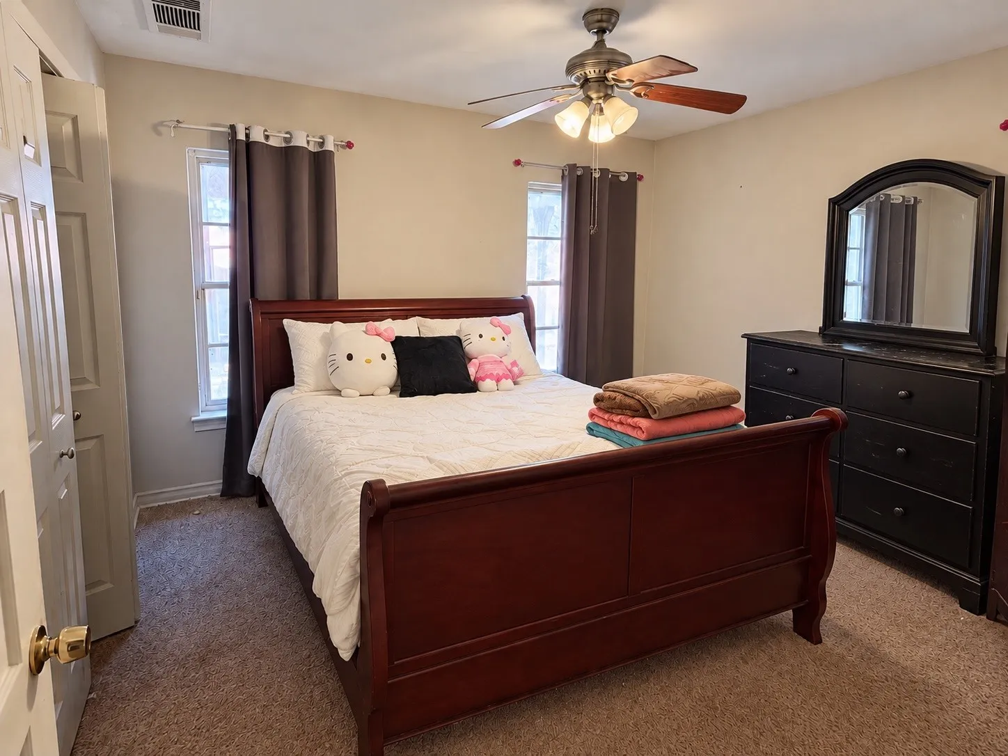Ceiling fan with integrated lighting, two windows with window treatments, wall-to-wall carpeting, and a built-in closet with a paneled door