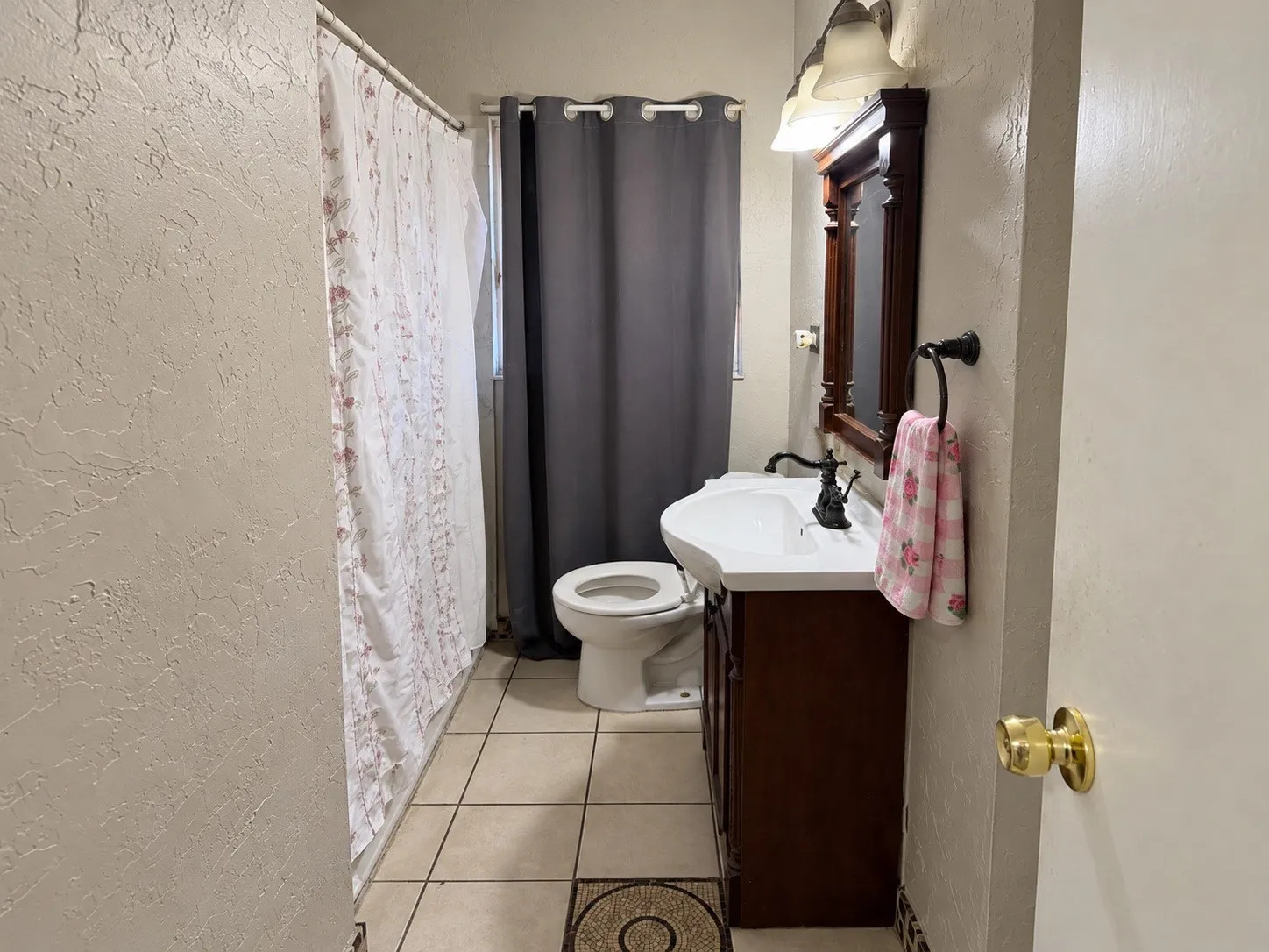 Recessed lighting, wood-finish vanity, integrated sink, bronze-finish faucet, and tiled flooring