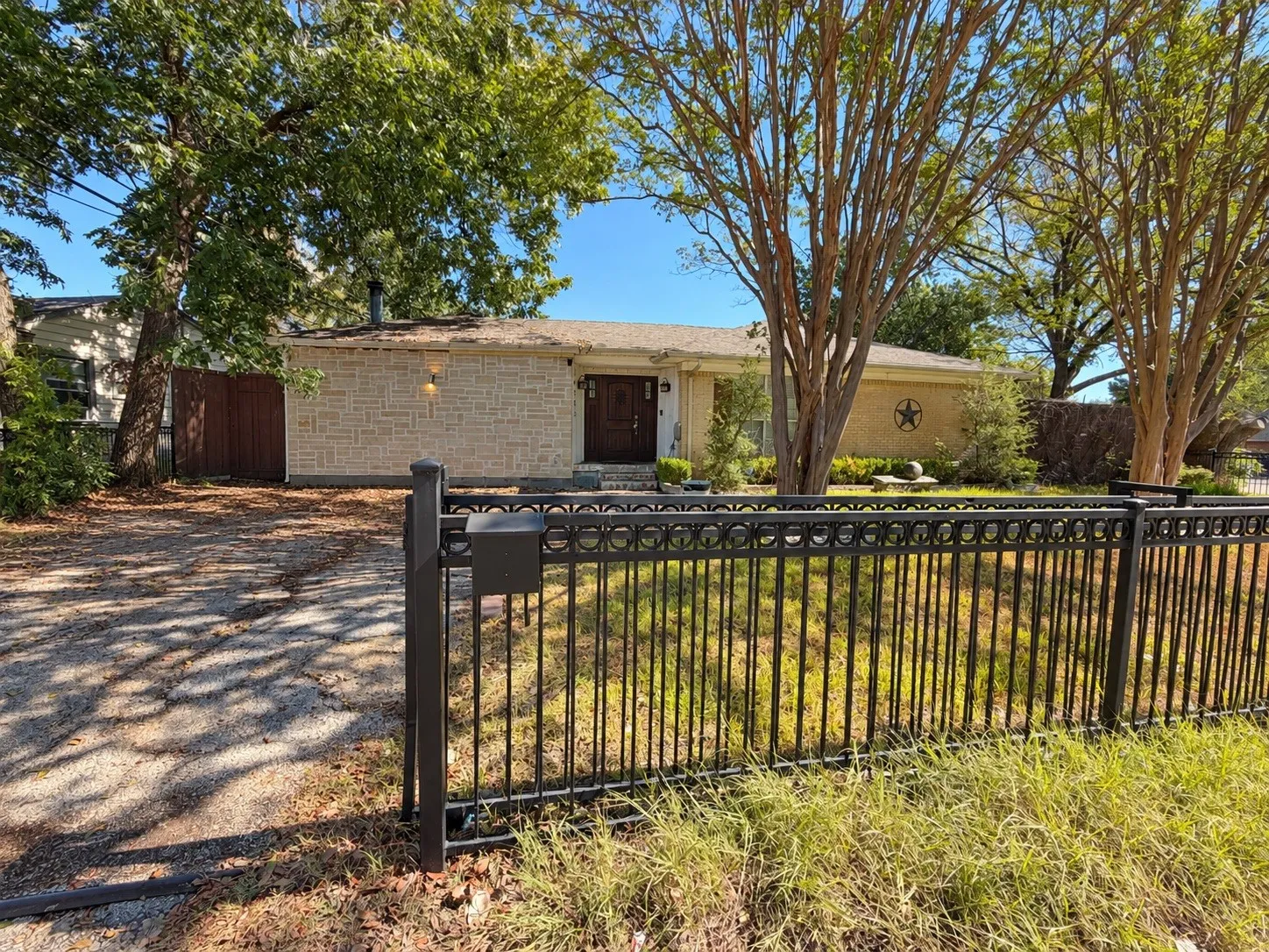 Stone veneer exterior, dark wood entry door, and a black wrought iron fence