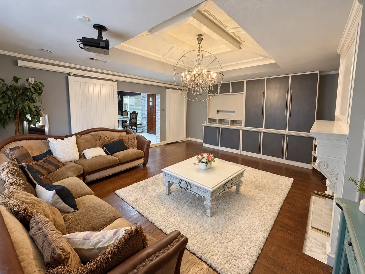 Hardwood-style flooring, a decorative chandelier, recessed ceiling lighting, a built-in entertainment center, and a projector system