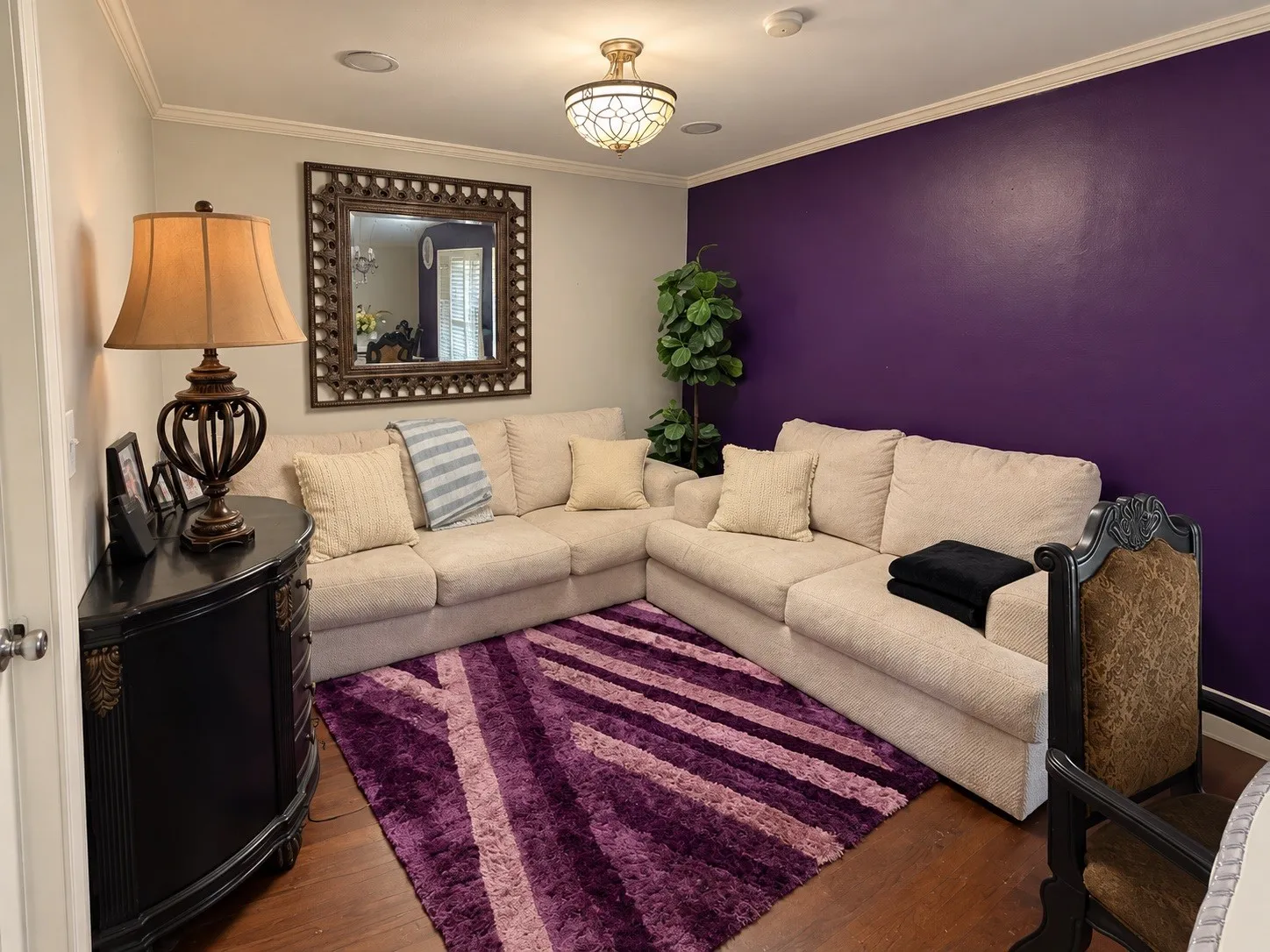 Wood-finish flooring with crown molding and a decorative ceiling light fixture