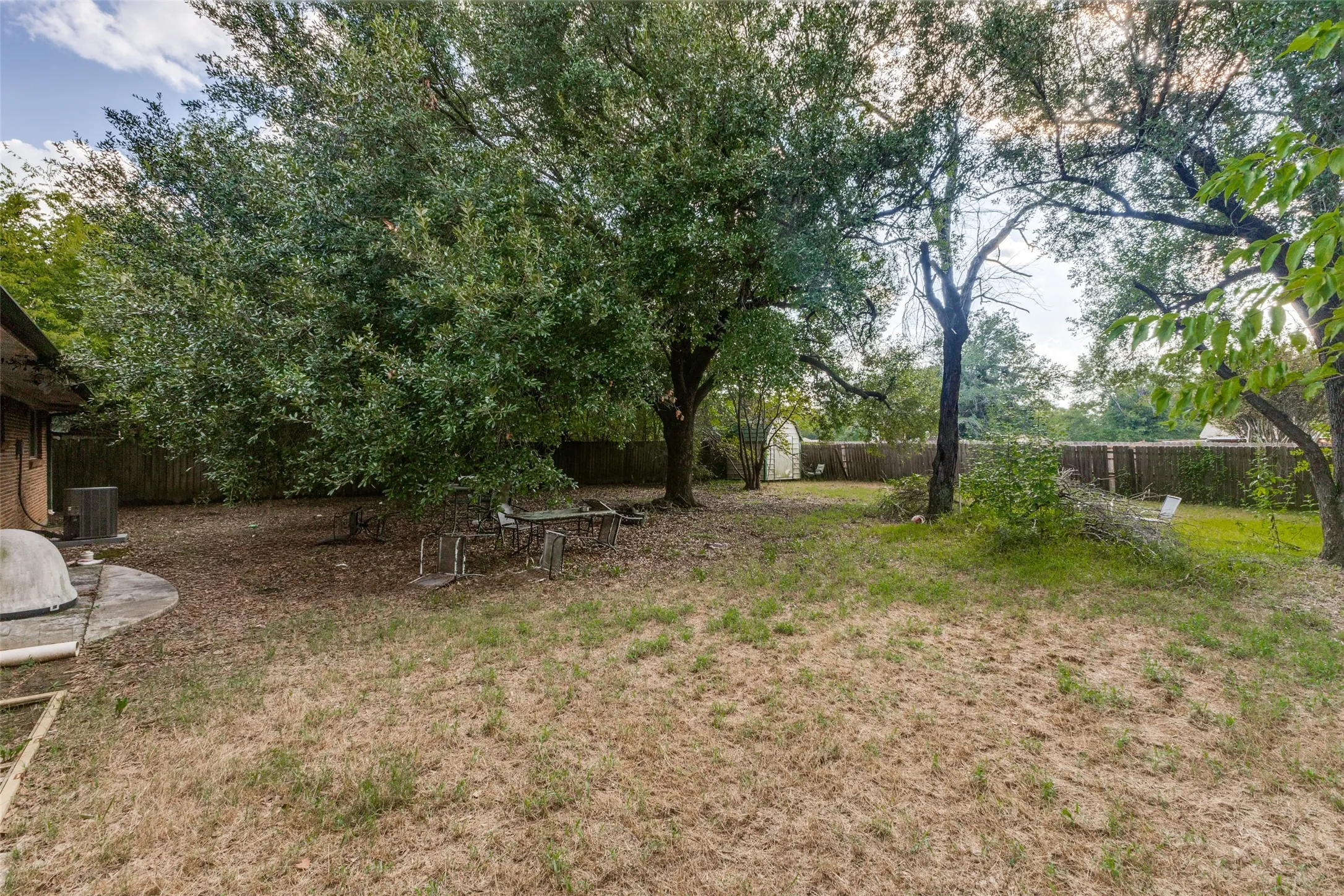 Fenced backyard with an outdoor structure and a patio area