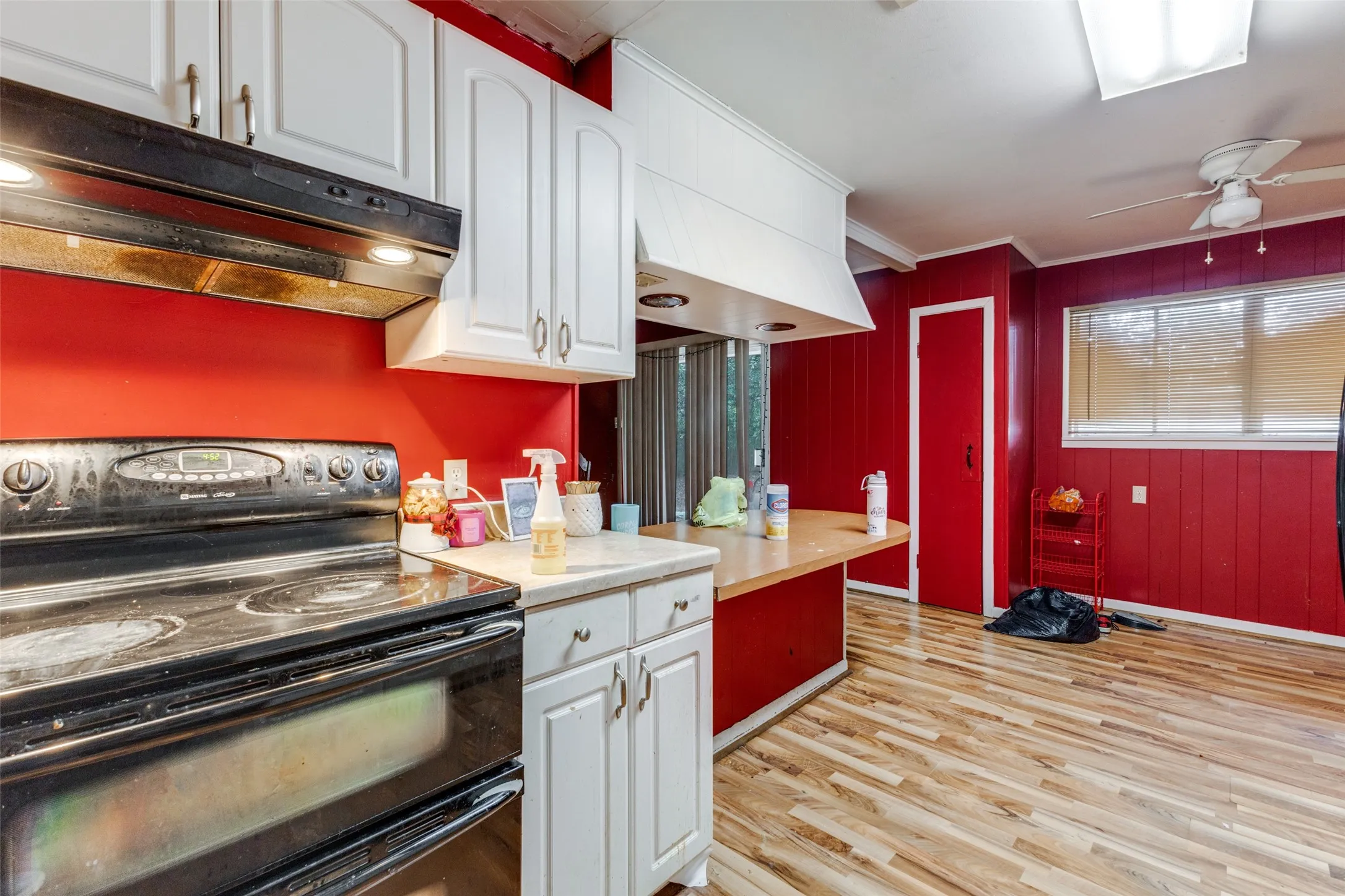 Kitchen with range with two ovens, white cabinetry, light countertops, under cabinet range hood, and light wood-style floors