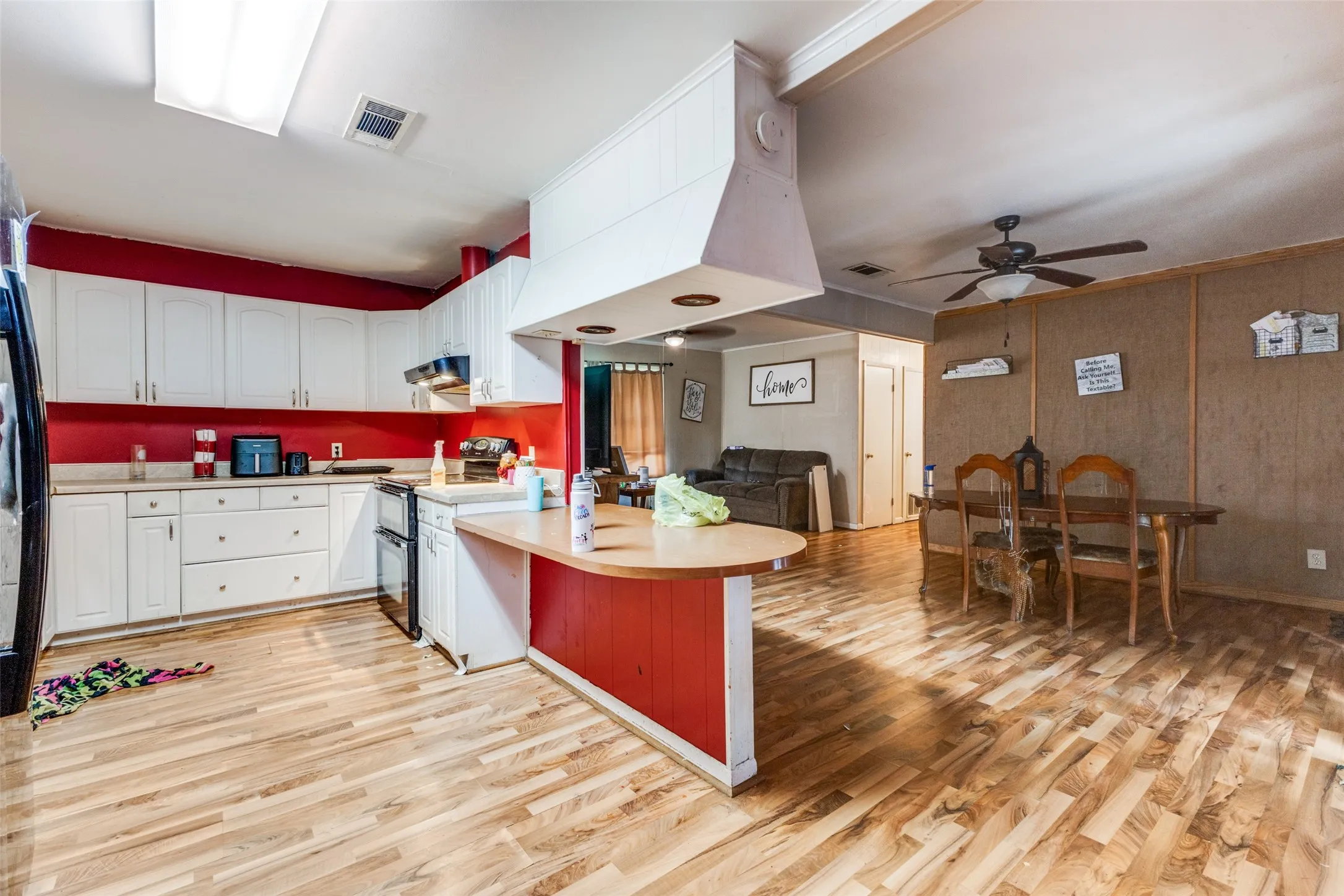 Kitchen with white cabinets, a peninsula, light countertops, and black appliances