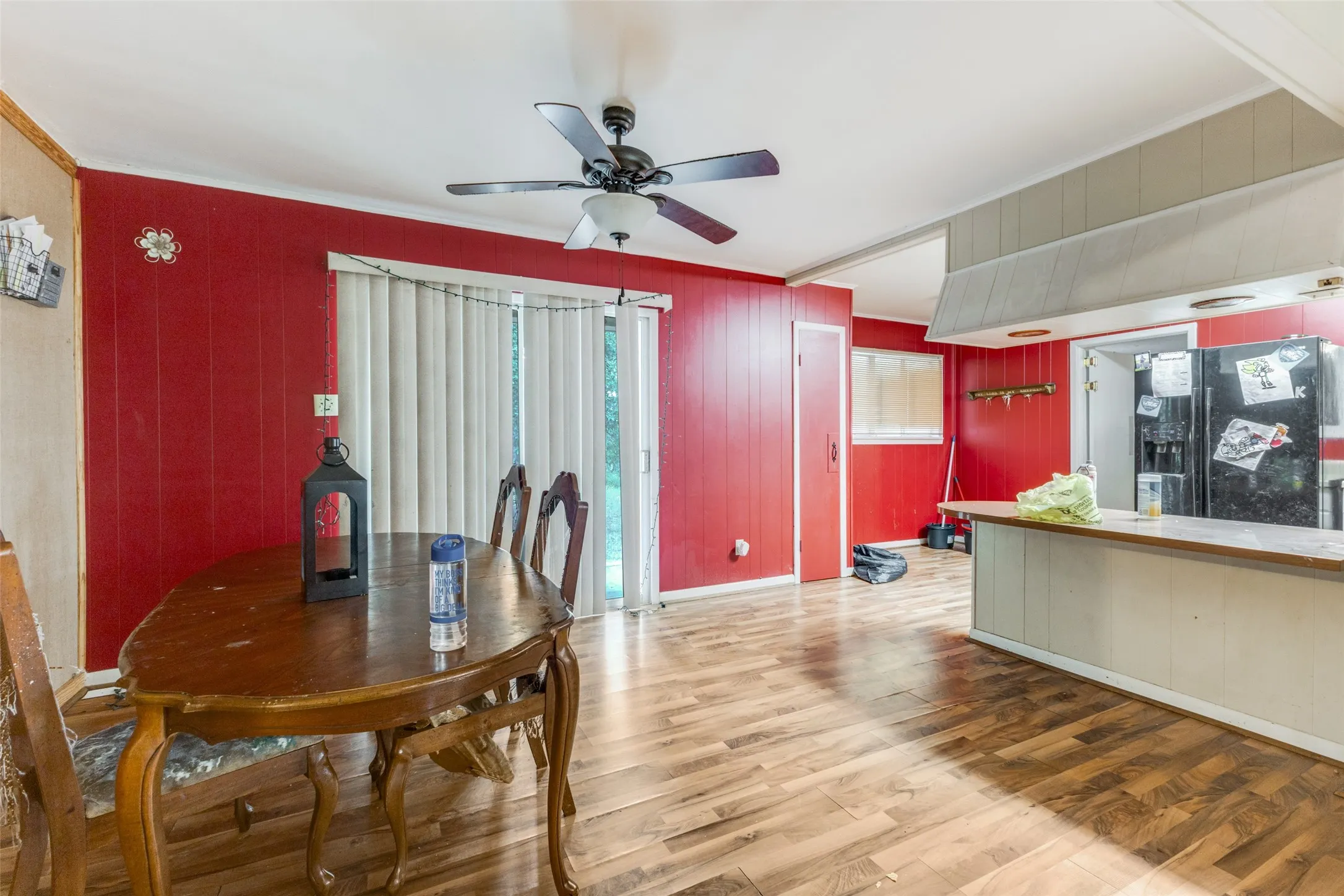 Dining area featuring light wood finished floors, ornamental molding, a ceiling fan, and wooden walls