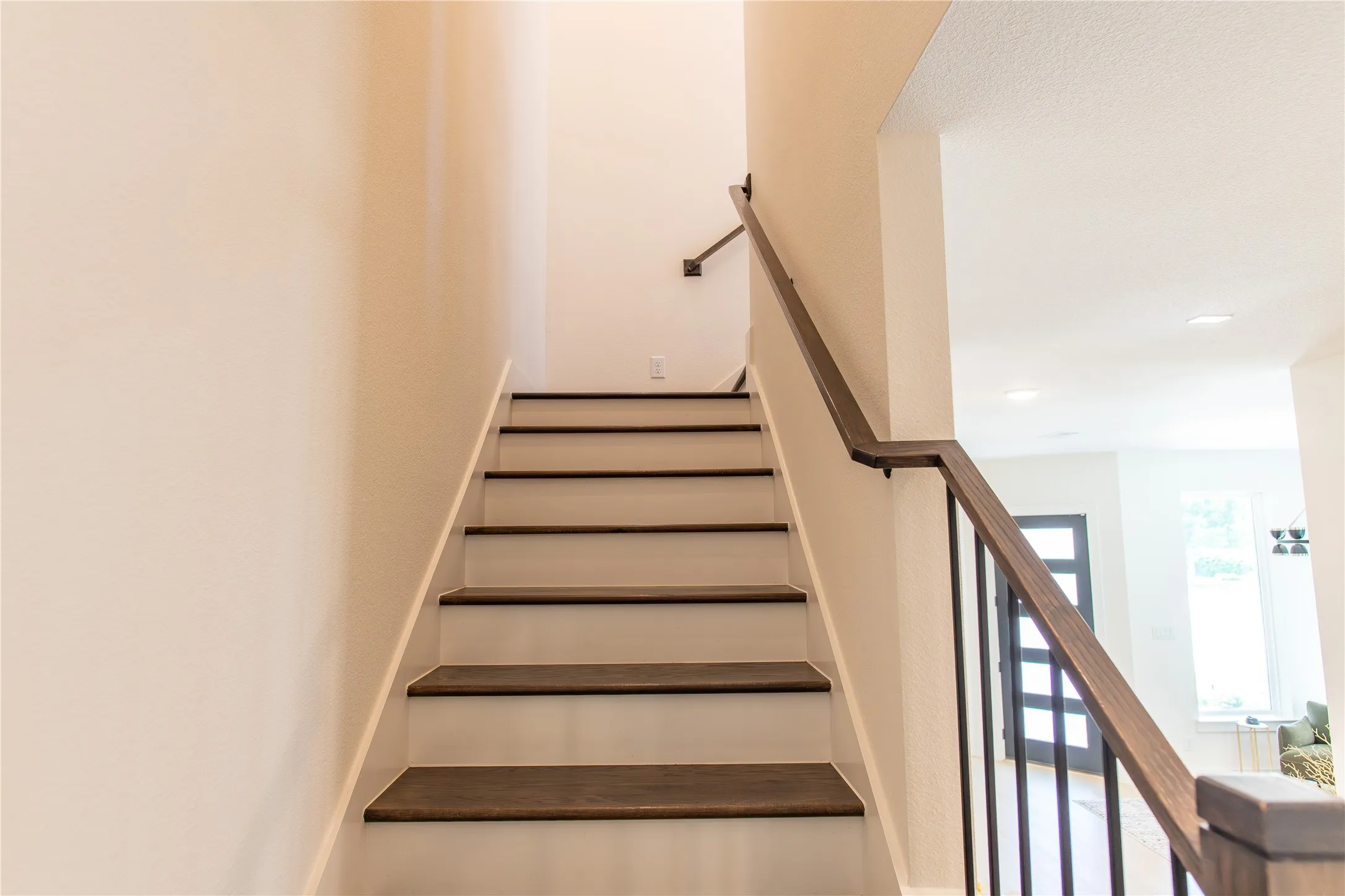 Staircase featuring wood-finish treads, white risers, and a contemporary wood and iron railing