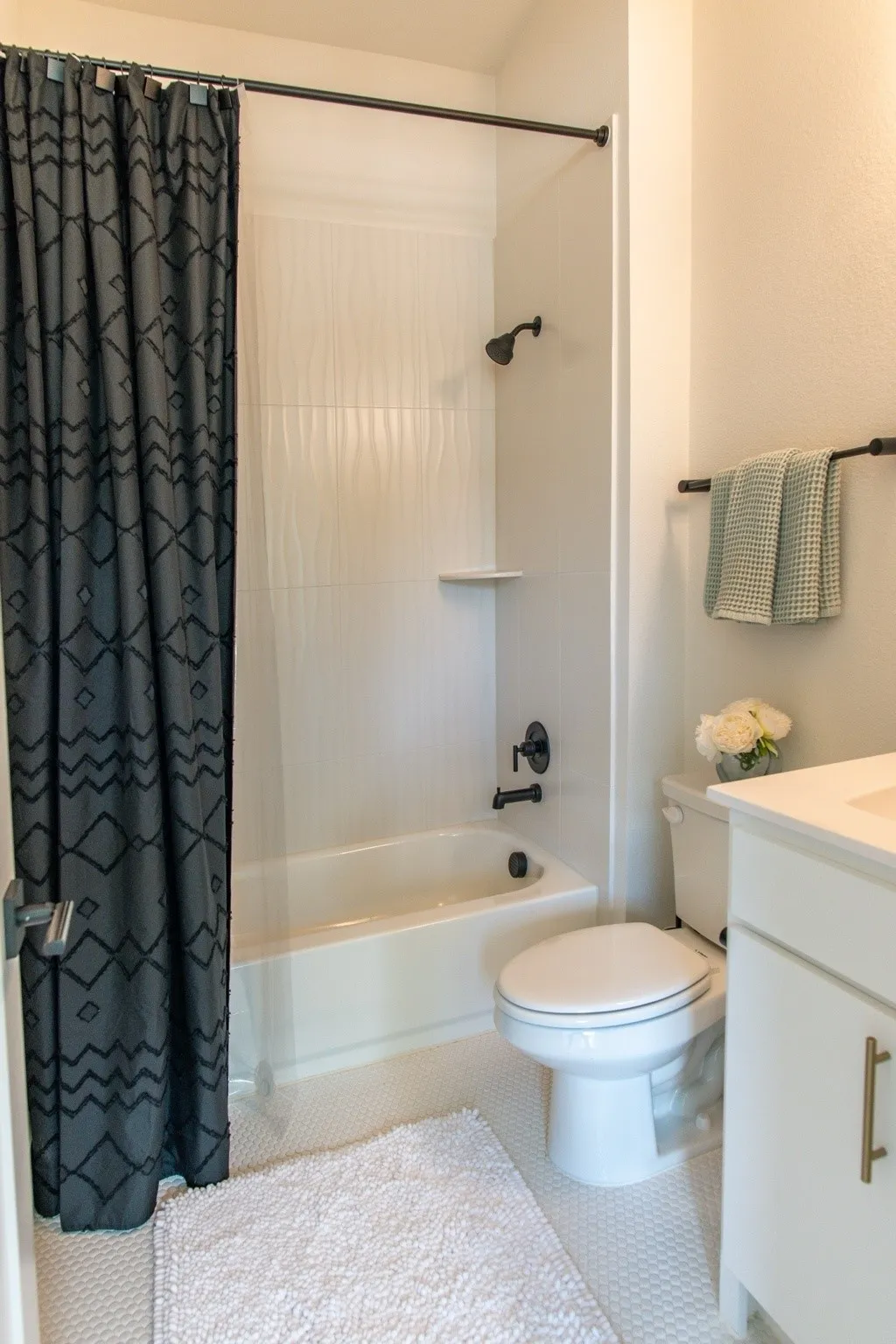 Bathroom featuring a white bathtub, black shower fixtures, and textured white shower wall paneling