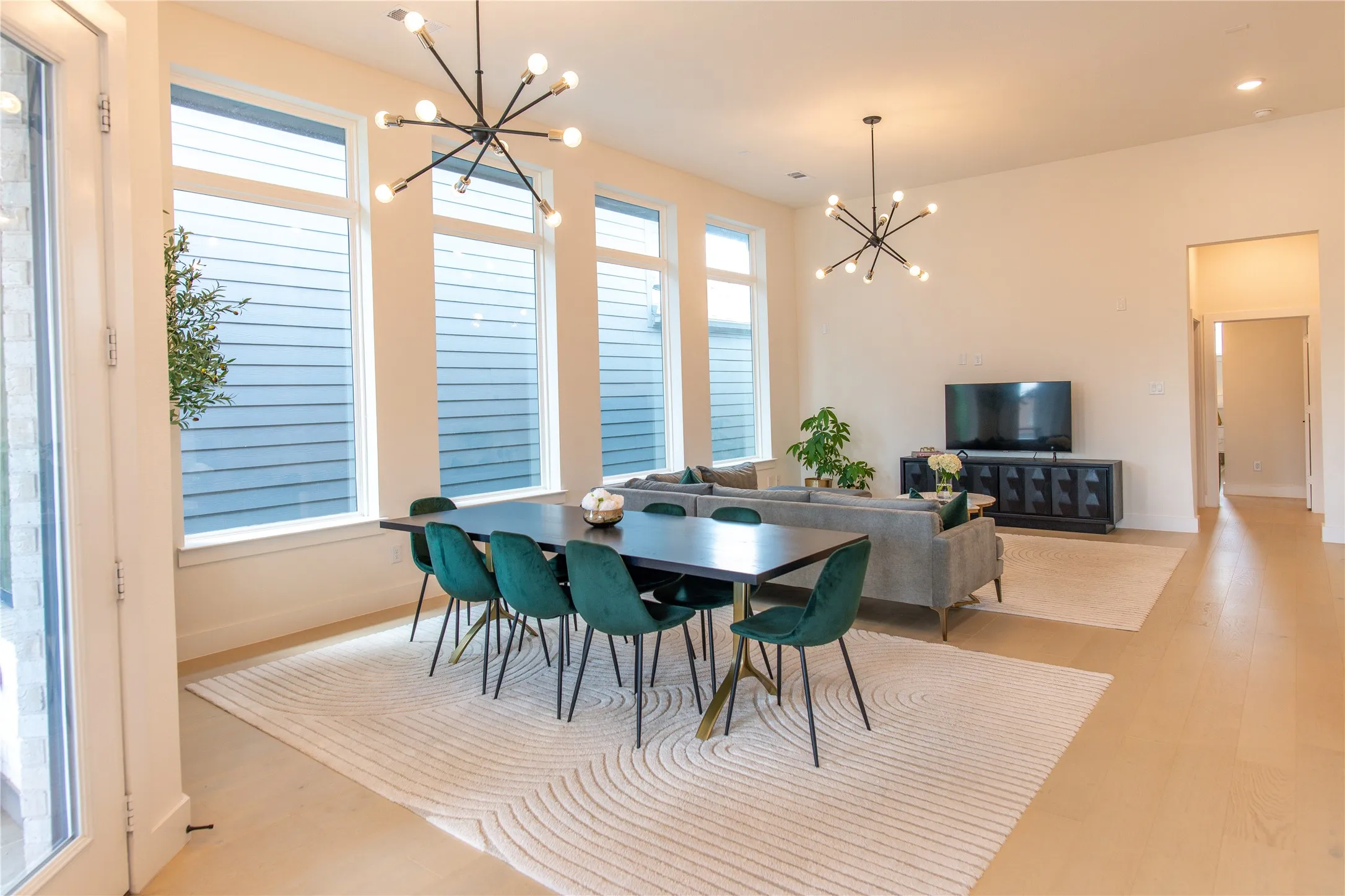 Open-concept living space featuring high ceilings, light wood-finish flooring, and tall windows