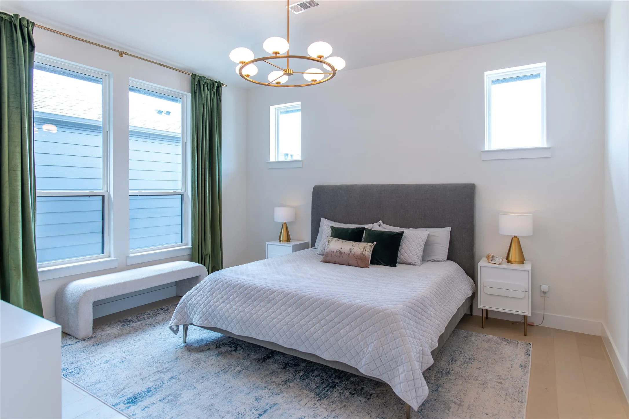 Bedroom featuring light wood-finish flooring, white walls, and multiple windows