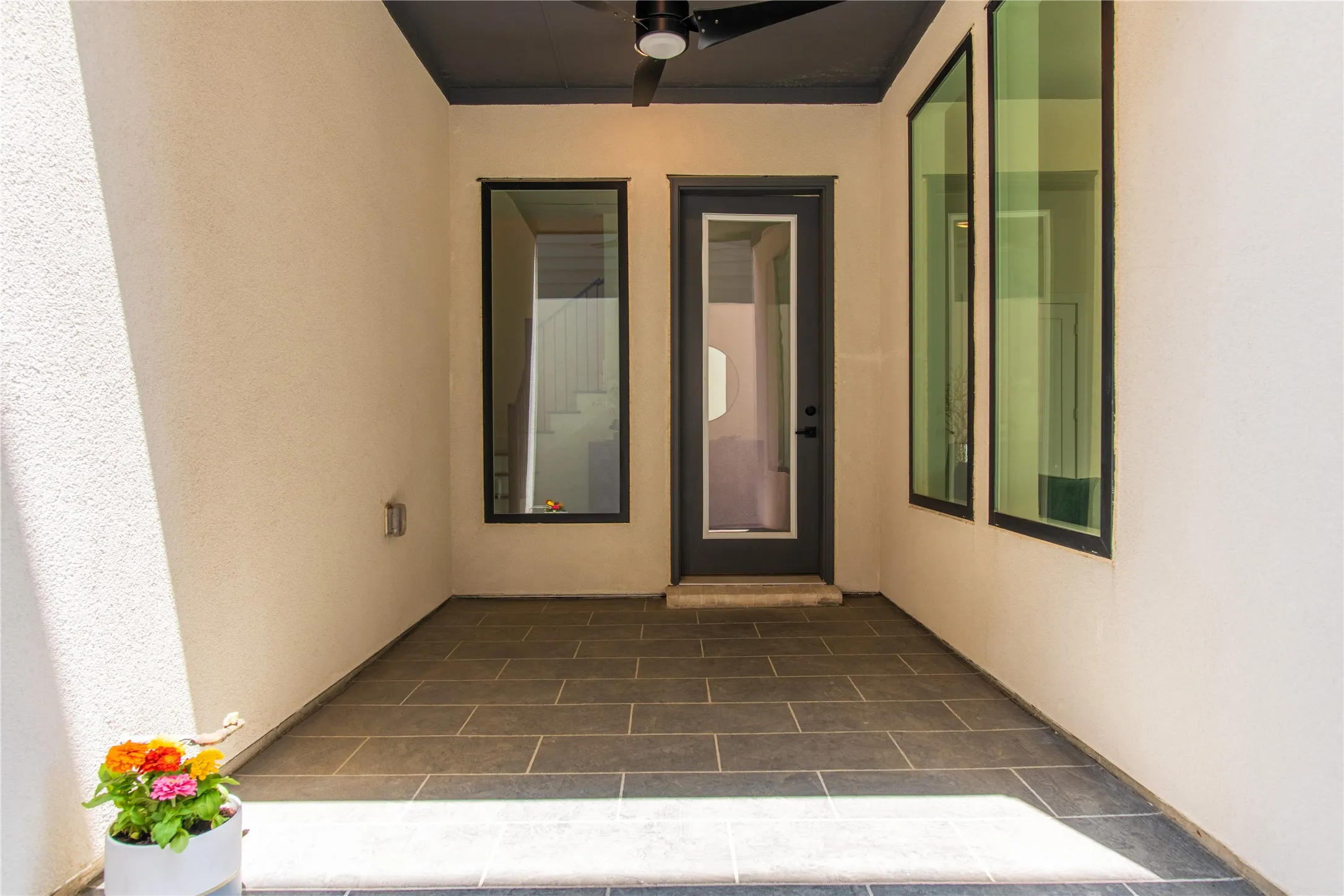 Covered patio area, black ceiling fan, and multiple vertical windows