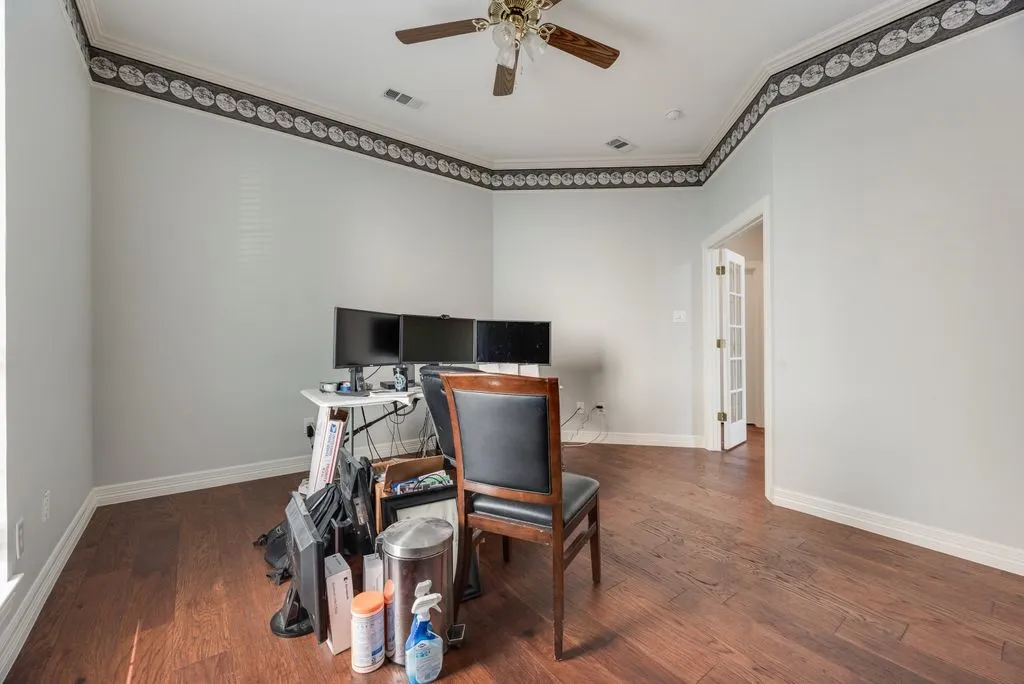 Spacious room featuring wood-finish flooring, light-toned walls, and a decorative border