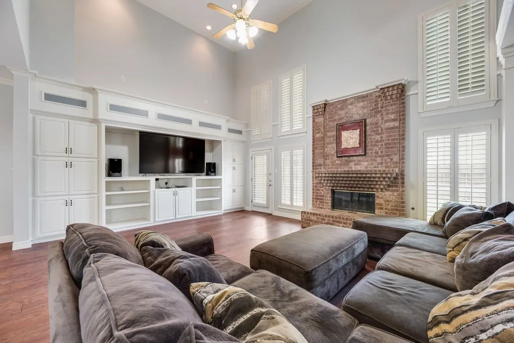Living area featuring high ceilings, wood-finish flooring, and a brick fireplace