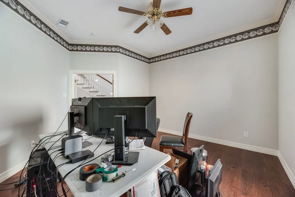 Interior room featuring wood-finish flooring, white baseboards, and crown molding