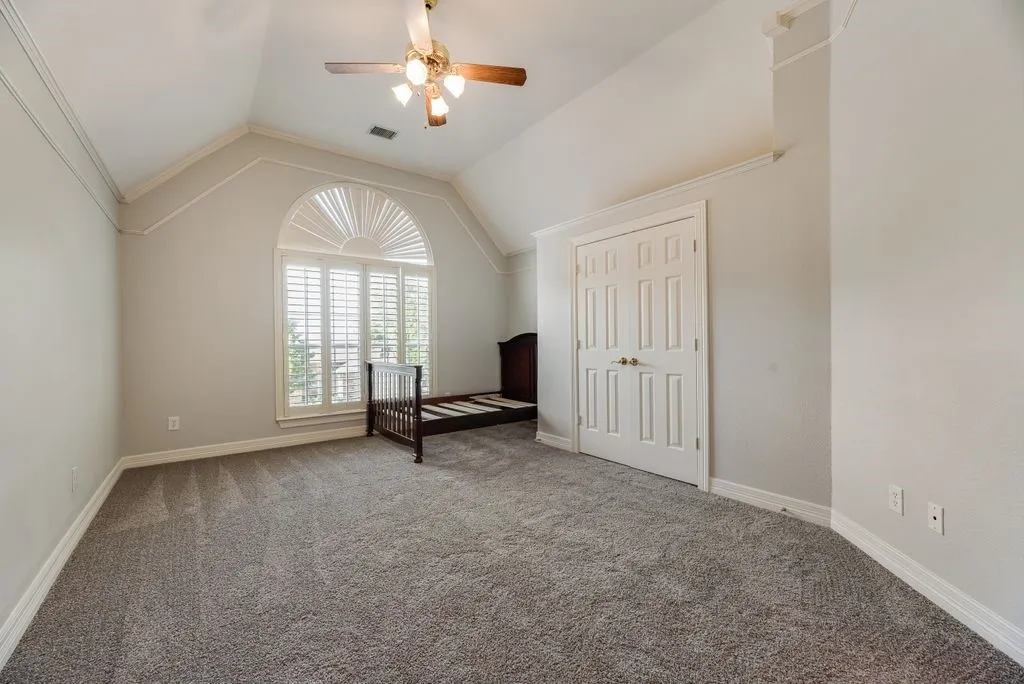 Vaulted ceiling room with an arched window featuring plantation shutters