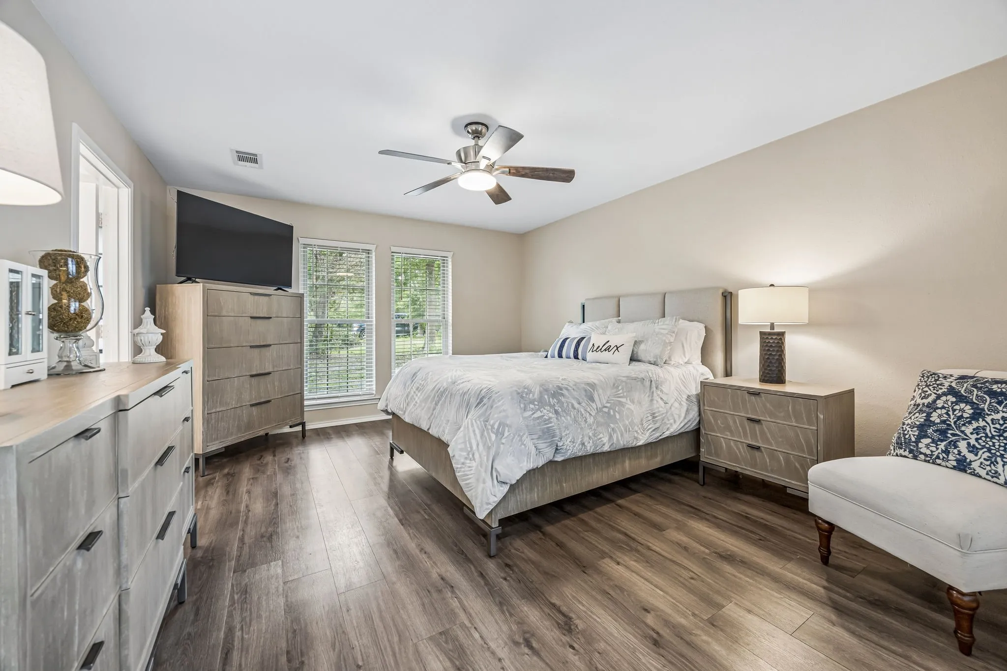 The spacious primary bedroom has easy care laminate flooring, ceiling fan, lush views and en suite bathroom.