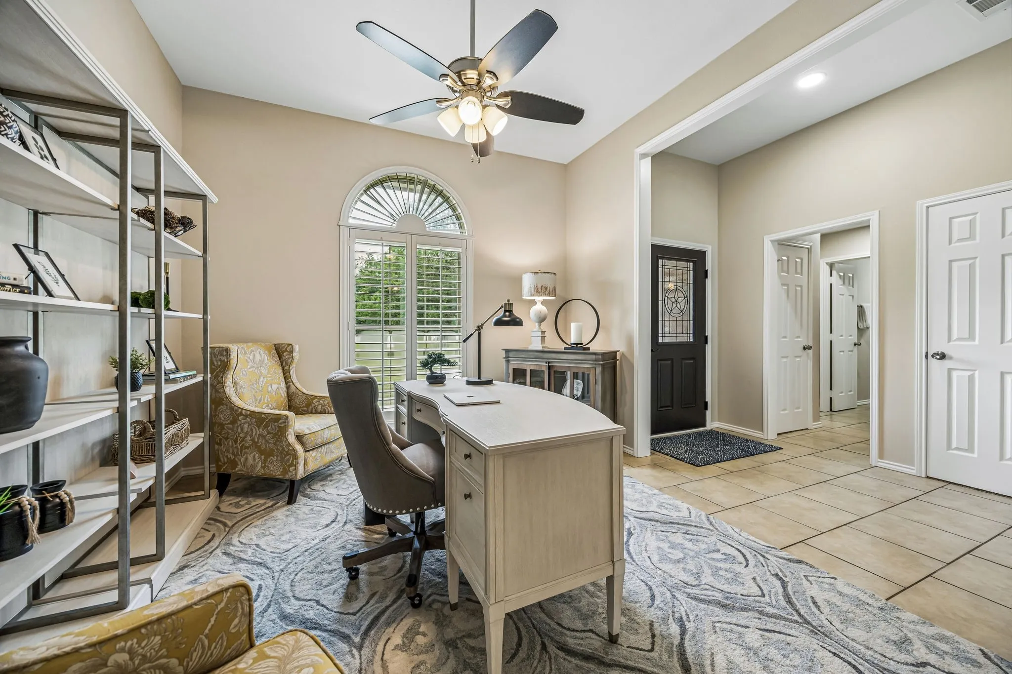 The dining space is currently used as an office for work from home. This area boasts views of the front yard, plantation shutters, ceiling fan and tile flooring.