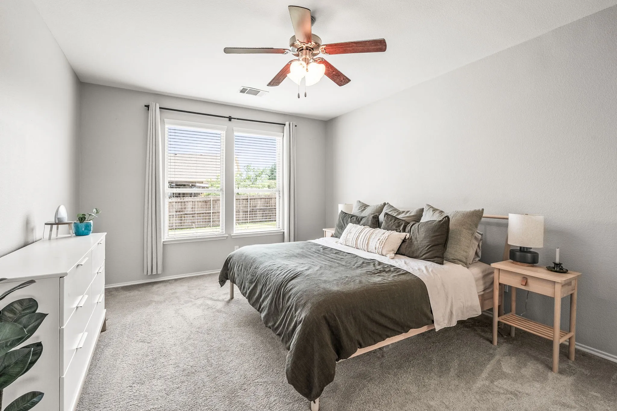 Carpeted room featuring a ceiling fan with integrated lighting, dual pane windows with blinds, and neutral wall tones
