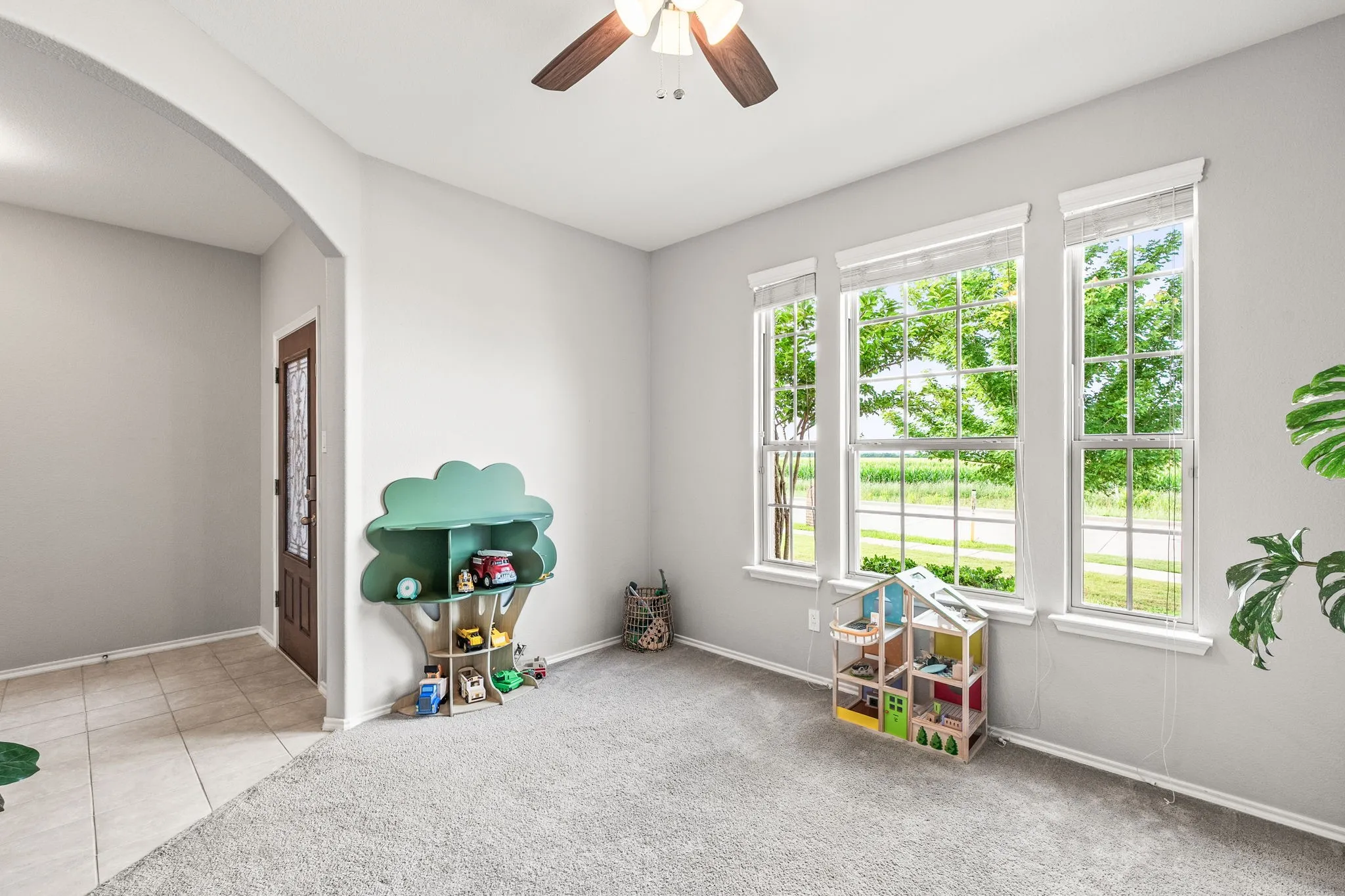 Living area featuring three large windows, light gray wall paint, and gray carpet flooring