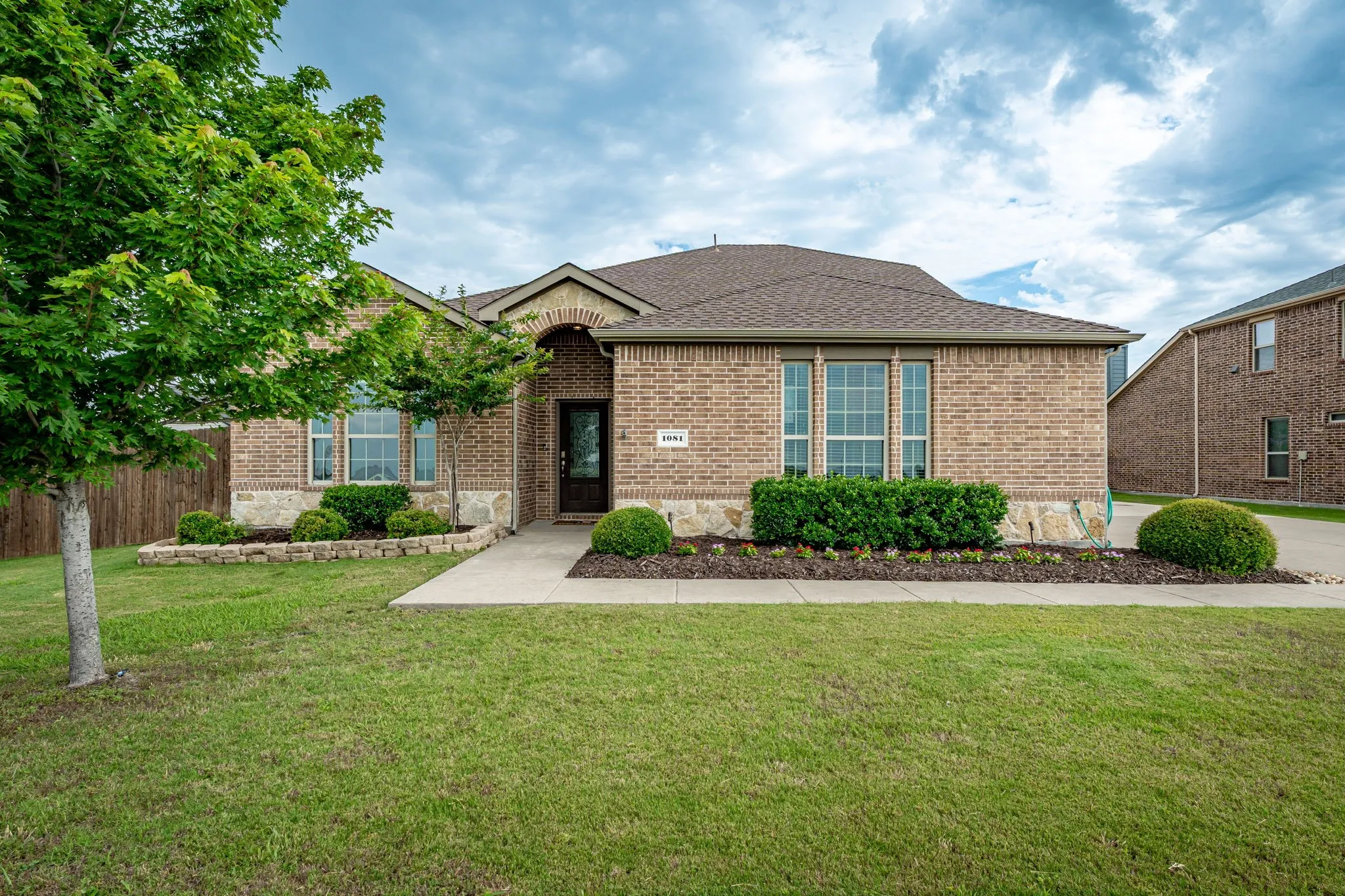 Brick exterior featuring a stone accent foundation, arched entry, and a gabled roof