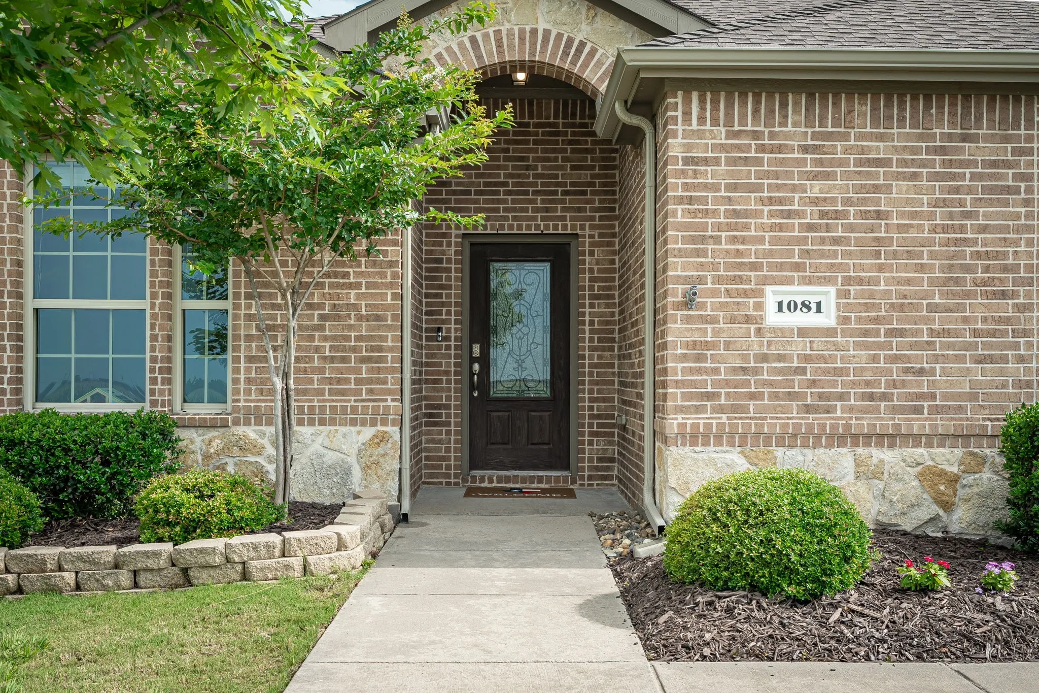 Brick exterior featuring stone accents and a covered entryway