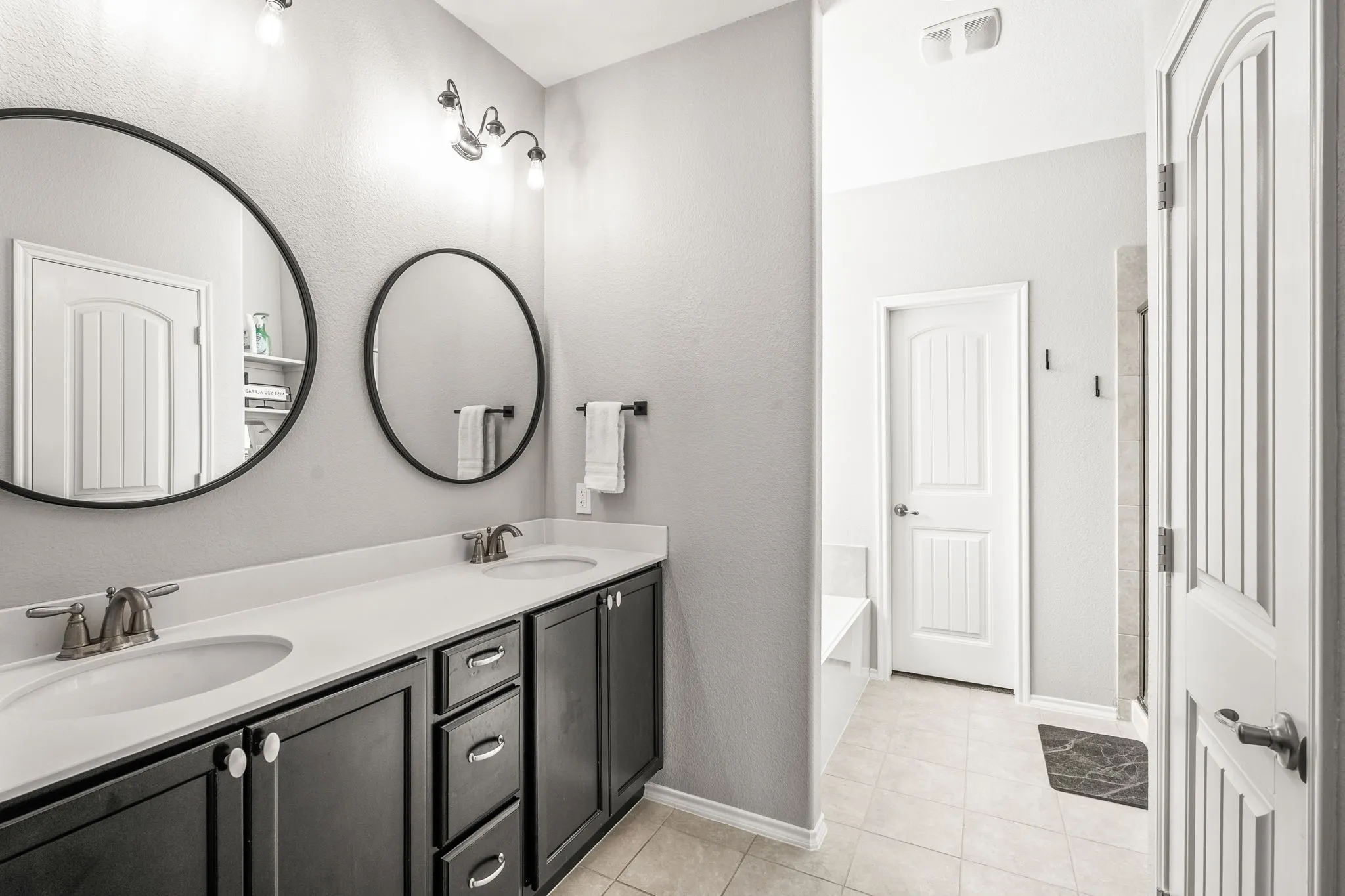 Dual vanity featuring dark wood cabinetry and white countertops