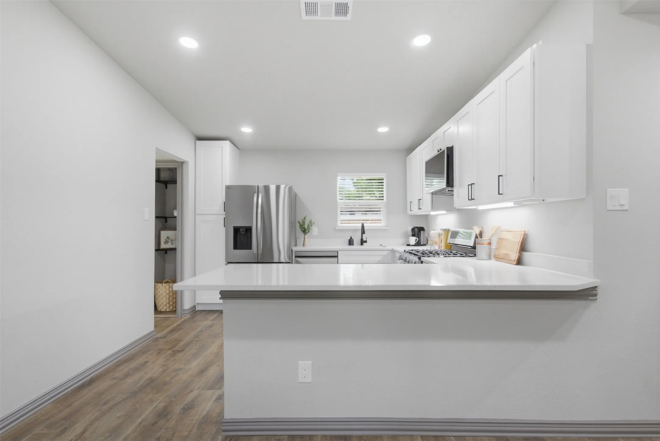 Entry space featuring a white paneled door with glass insert, wood-finish flooring, and recessed lighting