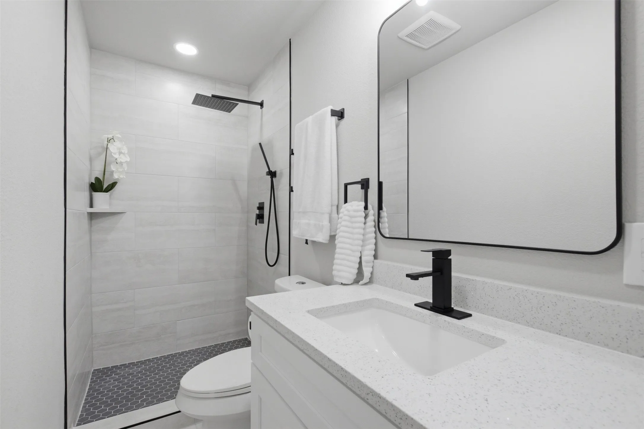 Modern kitchen featuring white shaker cabinetry with matte black hardware, stainless steel appliances, white countertops, and a stainless steel sink with a black faucet