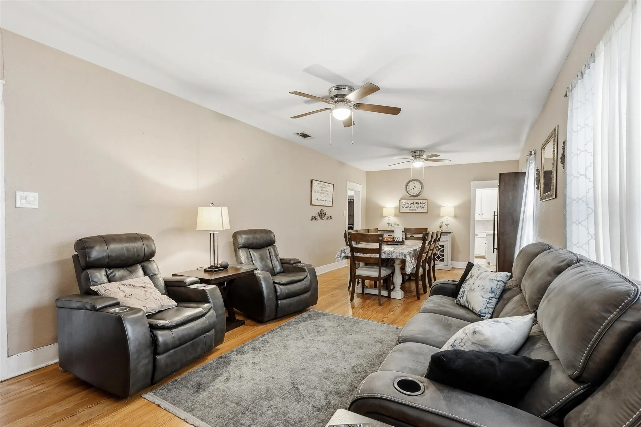 Open concept living area featuring wood-finish flooring, light neutral wall tones, and crown molding