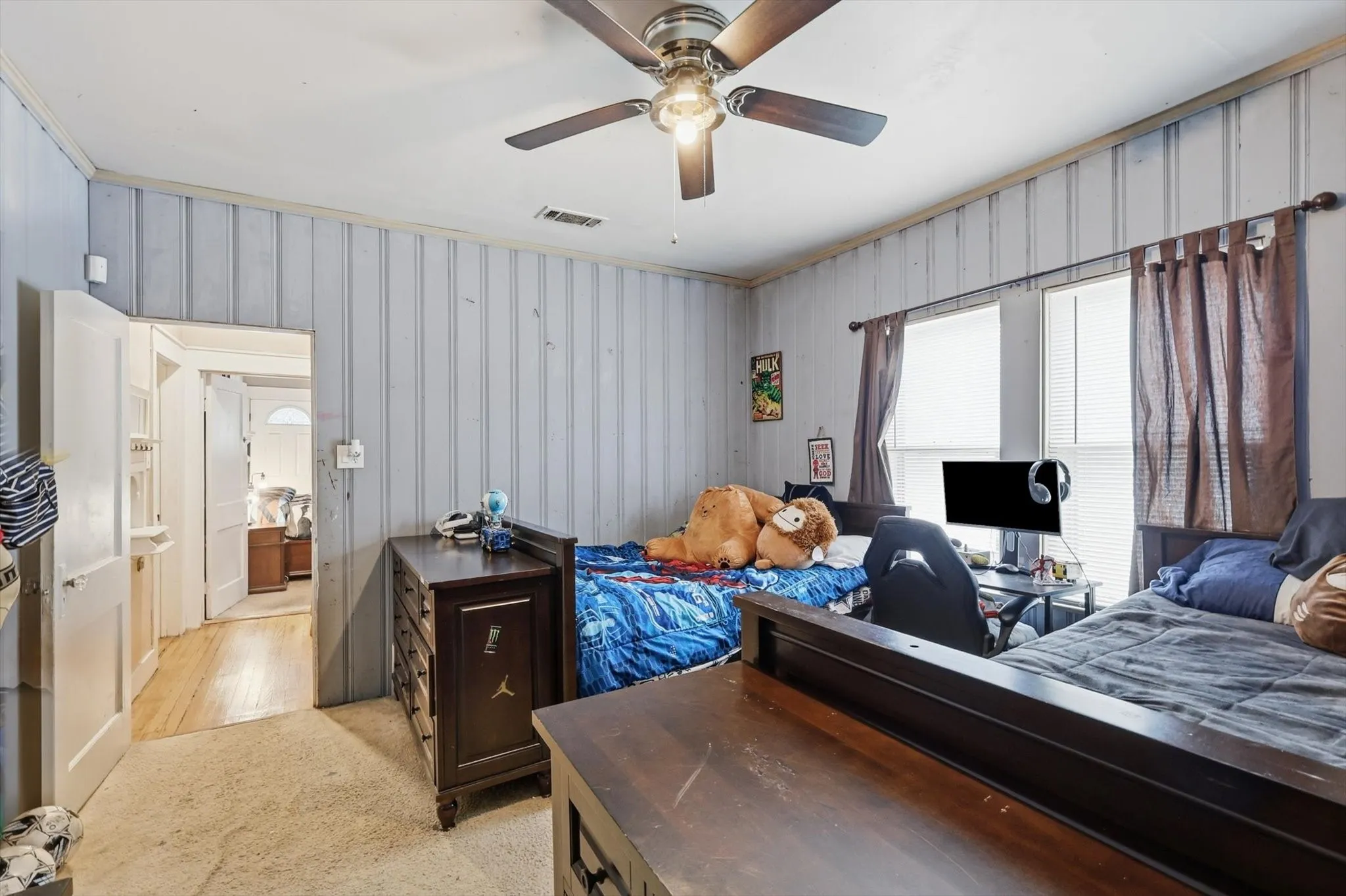 Room with vertical paneling, two windows, and a ceiling fan