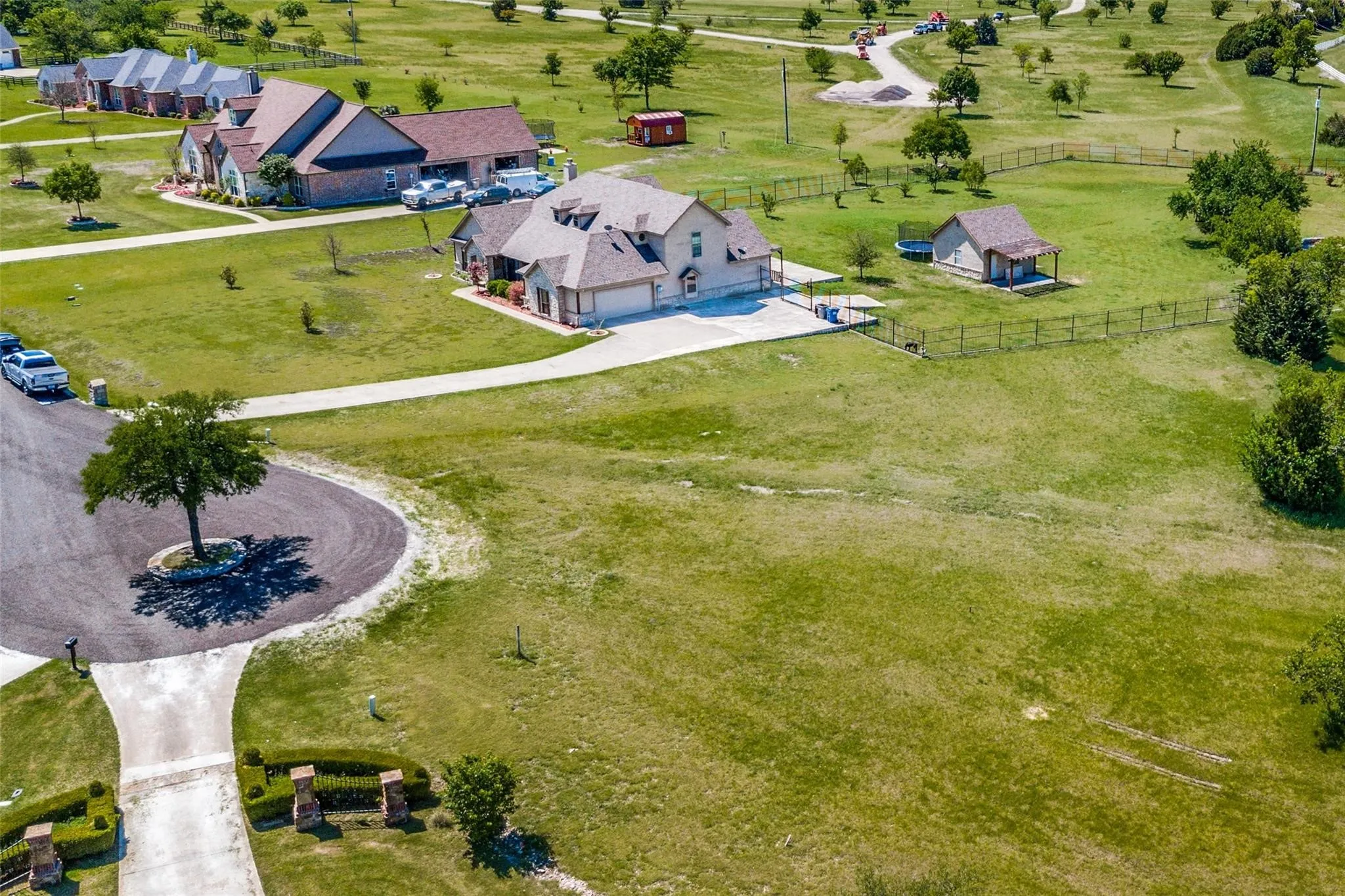 Expansive green landscape featuring a paved driveway, detached outbuilding, and mature trees